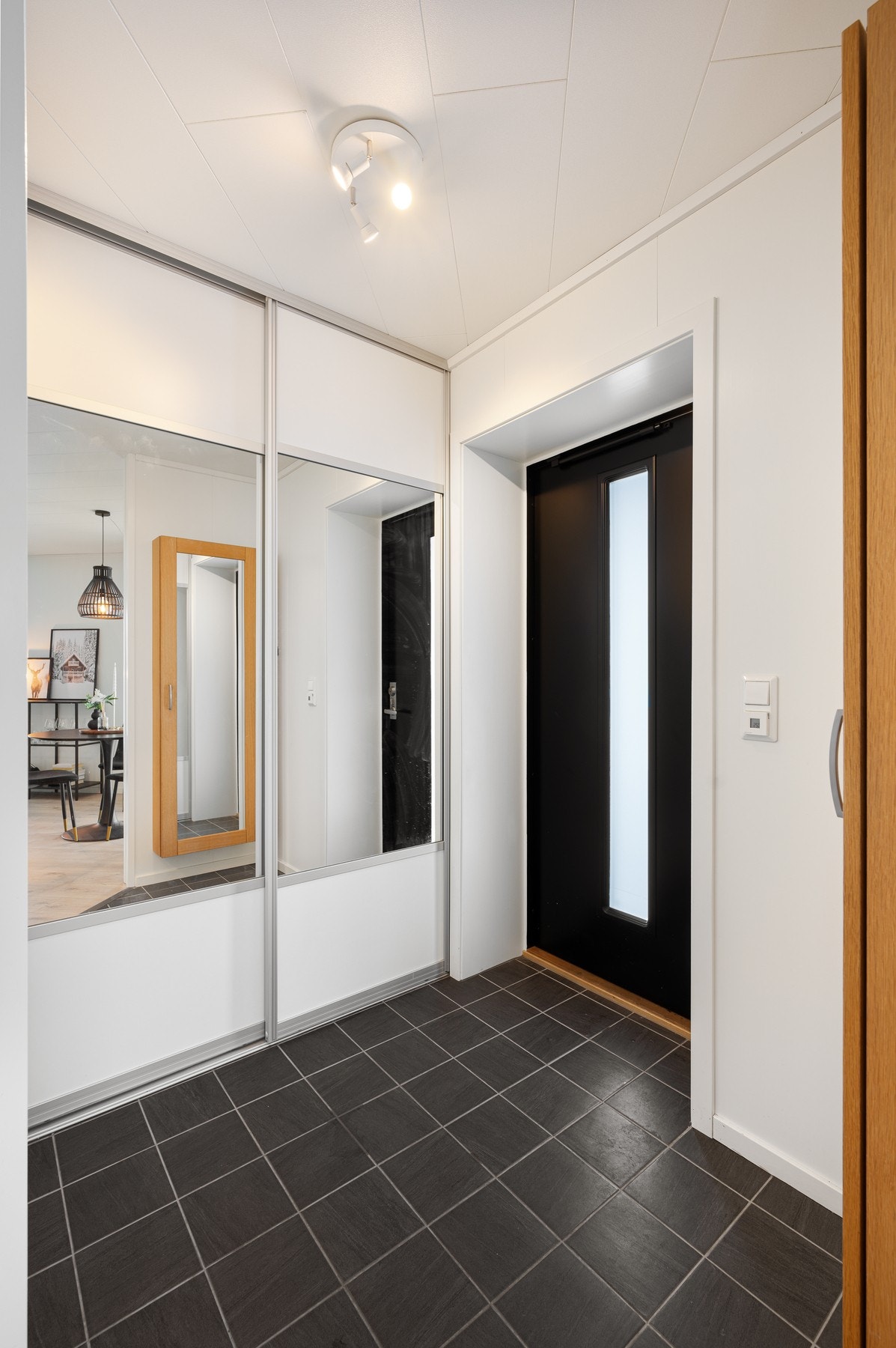 Flislagt entré med skyvedørsgarderobe for yttertøyet. Her er det varmekabler i gulv. Galleribilde