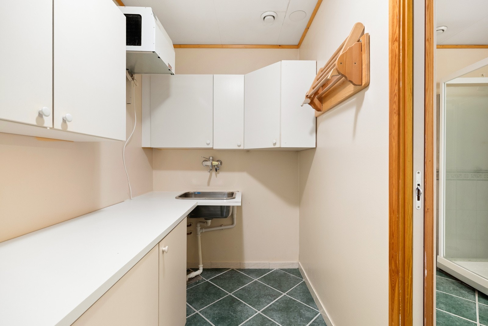 Praktisk vaskerom med tilkomst fra bad med fliser på gulv, utslagsvask og god lagringsplass. Siden boligen ligger i en toppetasje, har disse også god lagringplass på ståloft med tilkomst fra vaskerom. Galleribilde