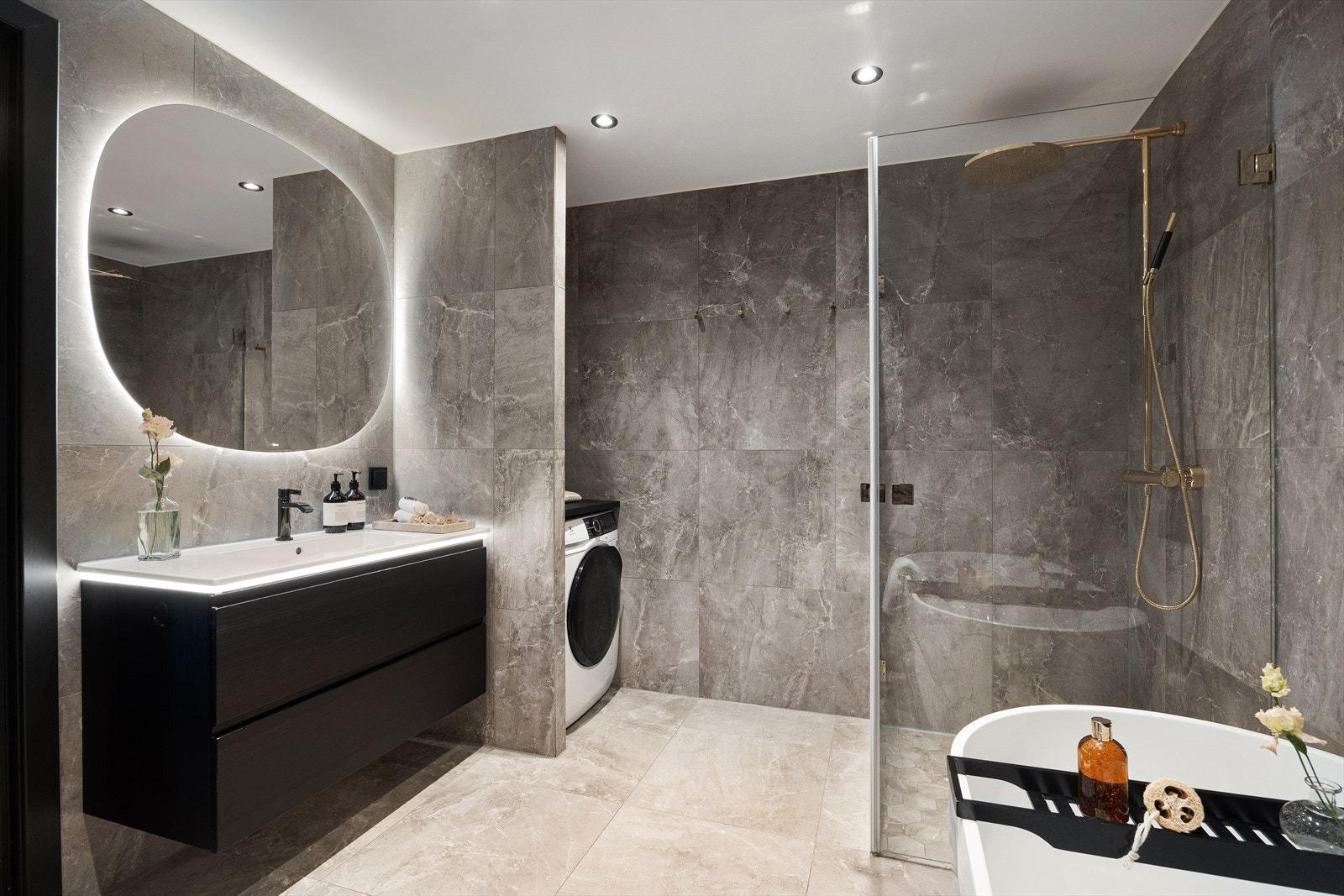 Badet er stilrent innredet med et servantskap med servant, speil med innebygd berøringslys, samt et vegghengt klosett. Praktisk vaskenisje med opplegg for både vaskemaskin og tørketrommel. Det er også plassbygde hyller i vaskenisjen. Galleribilde