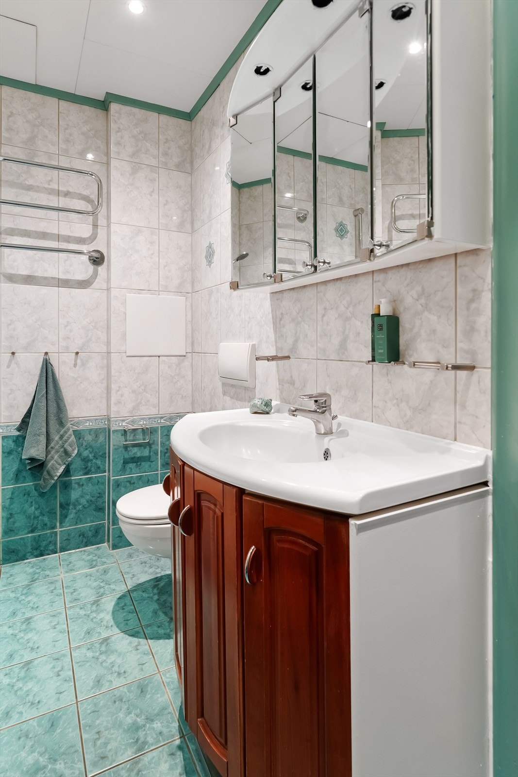 Baderommet er utstyrt med dusj i badekar, veggfestet klosett, opplegg for vaskemaskin og servant med innredning Galleribilde