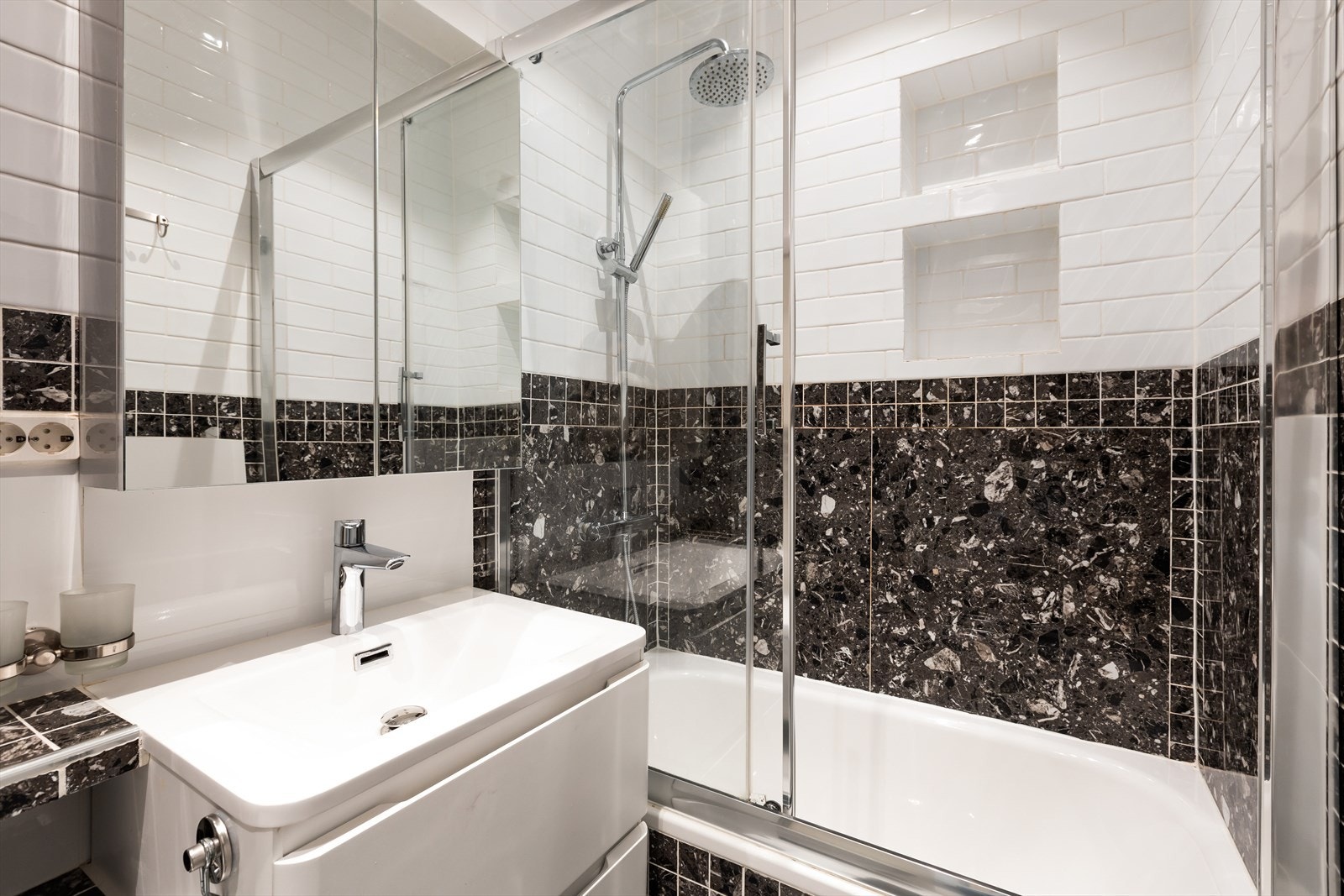 Stilrent bad med innredning bestående av nedfelt vask, benkeskap med glattefronter og overskap med speil fronter. Galleribilde