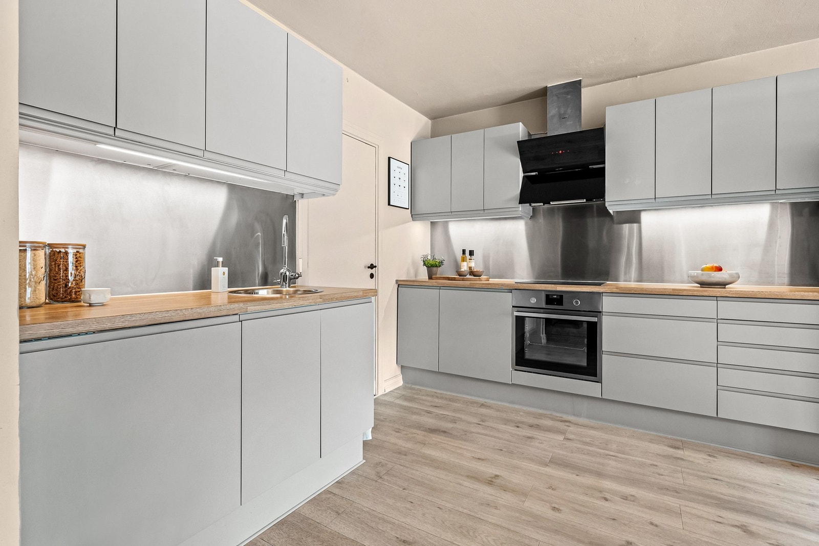 Hvitevarer som integrert induksjonsplatetopp, stekeovn, oppvaskmaskin og frittstående side by side kjøle- og fryseskap med innebygd vann- og ismaskin. Galleribilde