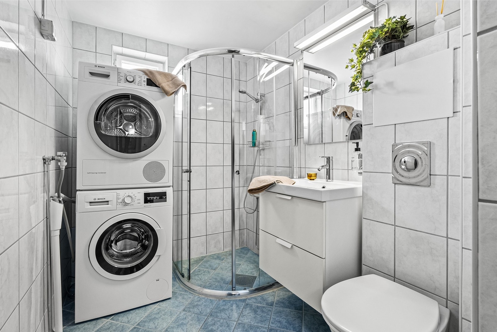 Pent flislagt baderom fra 2005 med gulvvarme og opplegg for vaskemsakin og tørketrommel. Dusjhjørne med skyvedør og sokkellist som hindrer vannsøl Galleribilde