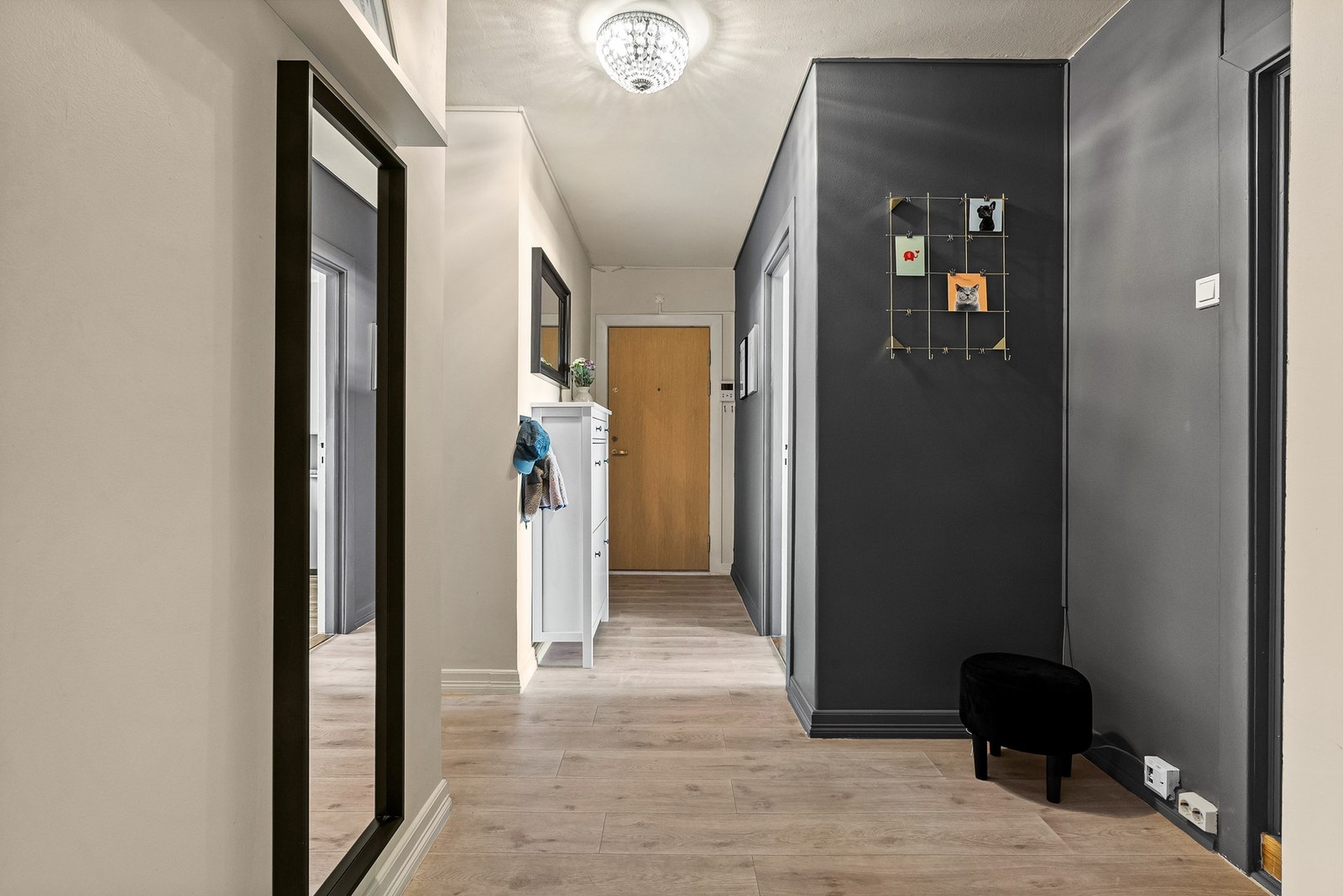 Glatte malte veggflater i beige og en hel kontrastvegg og dør i mørkt fargevalg. Det er plass til sittebenk til av og påkledning. Galleribilde