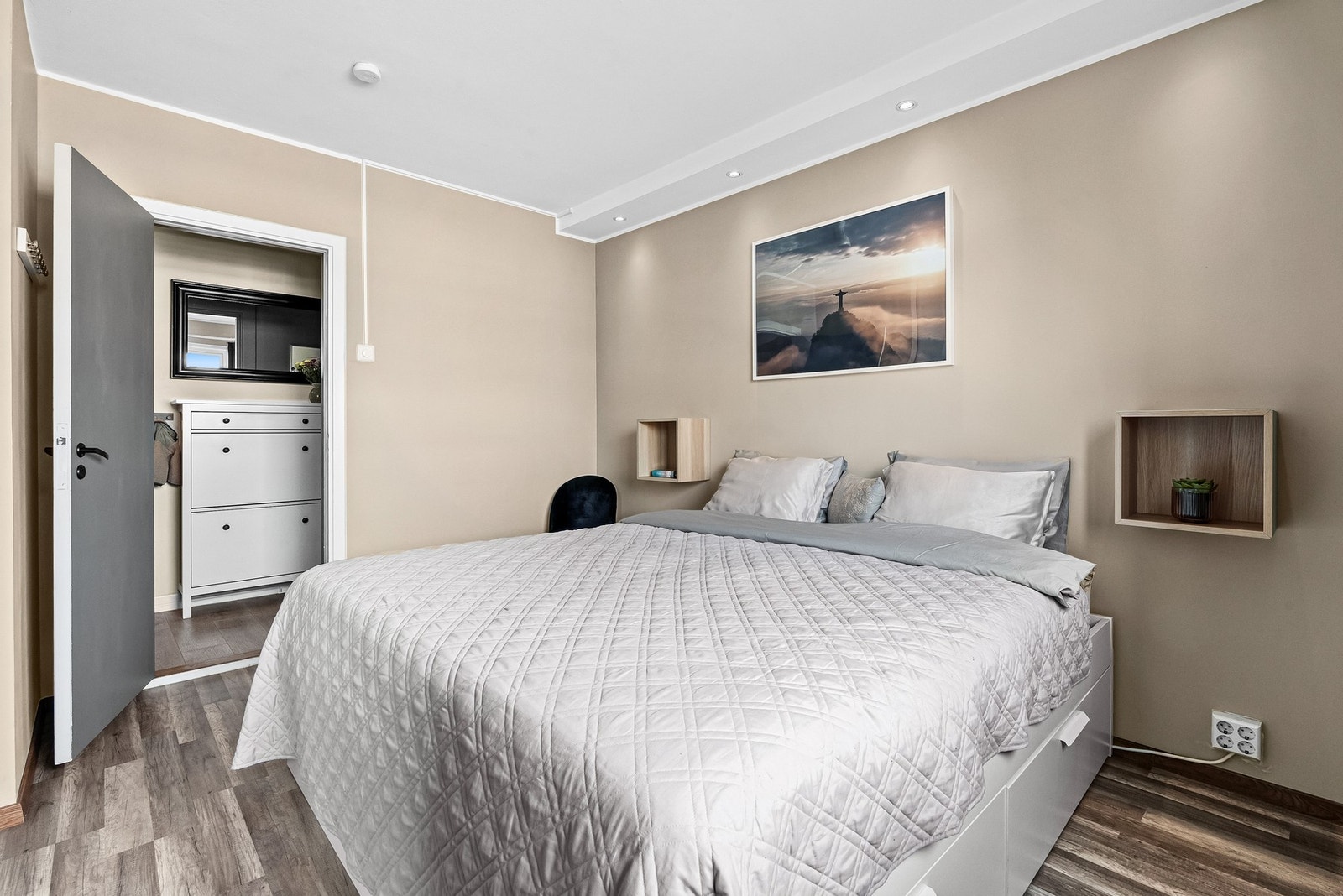 Videre inn til et stort og fint hovedsoverom med nedfelt lyskasse i tak, laminatgulv og glatte beigemalte overflater Galleribilde