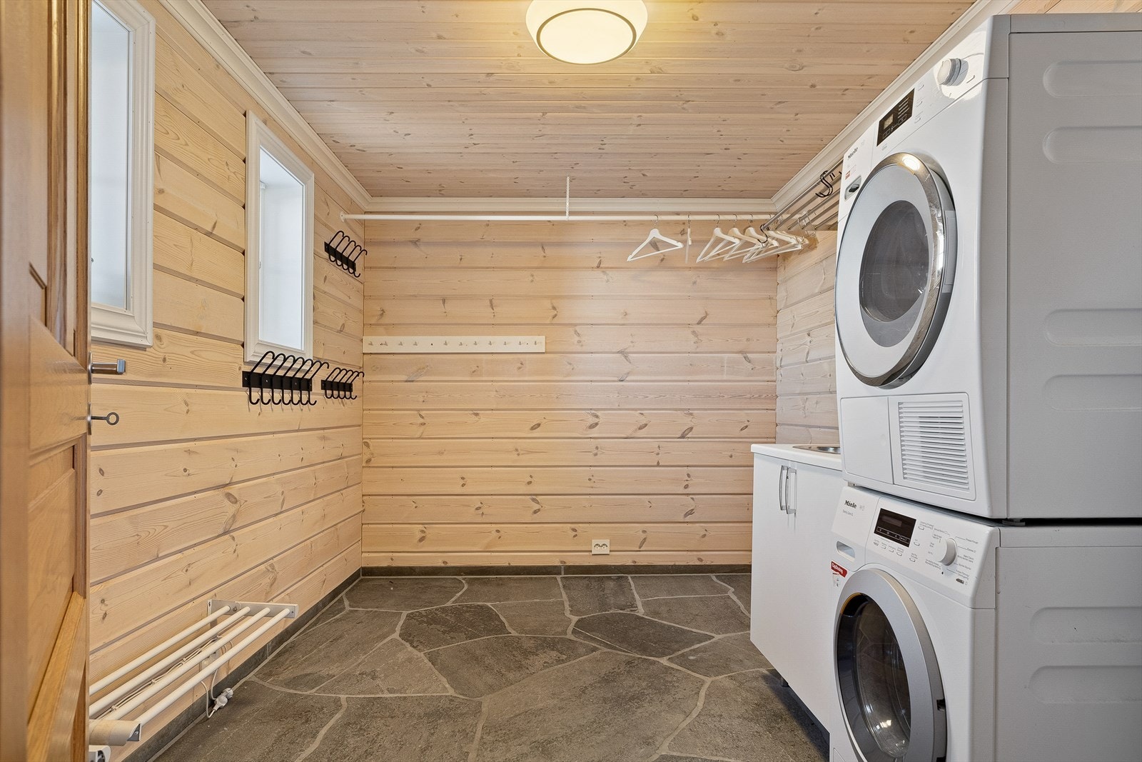 Fra gangen får du tilgang til et romslig vaskerom med gjennomtenkte løsninger, som gjør det enkelt å holde orden på alt utstyr. Galleribilde