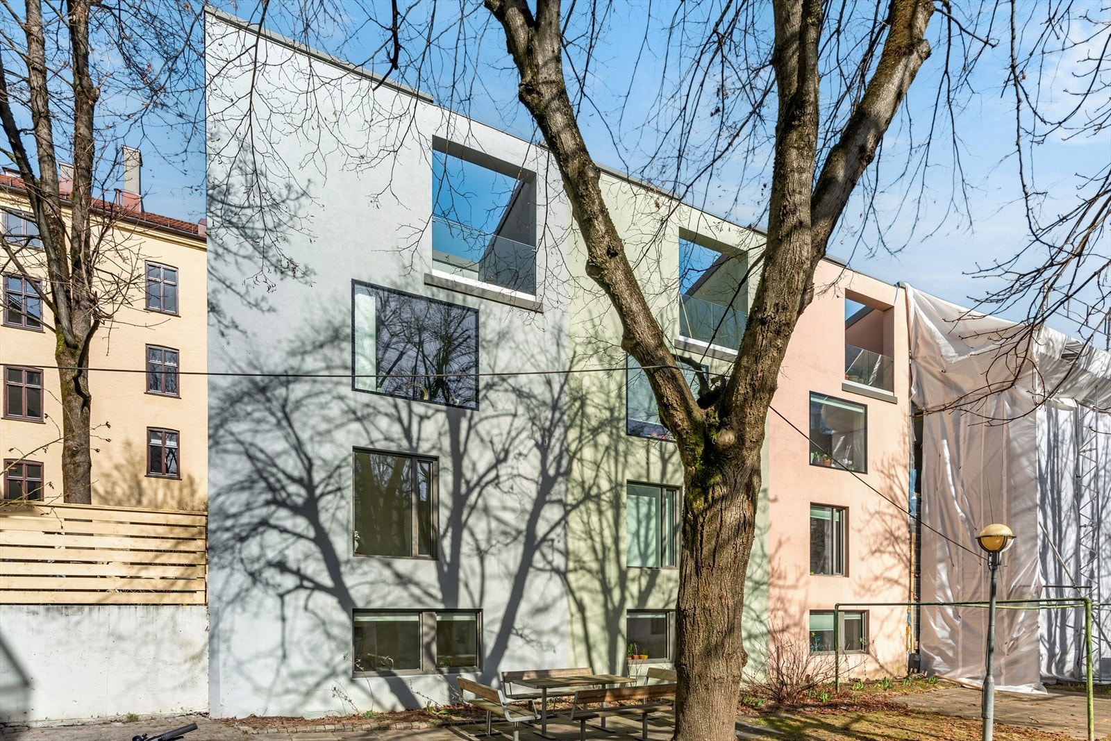 Omringet av trær i en lys og åpen bakgård finner du tre farveglade sammenkjedede byhus. Galleribilde