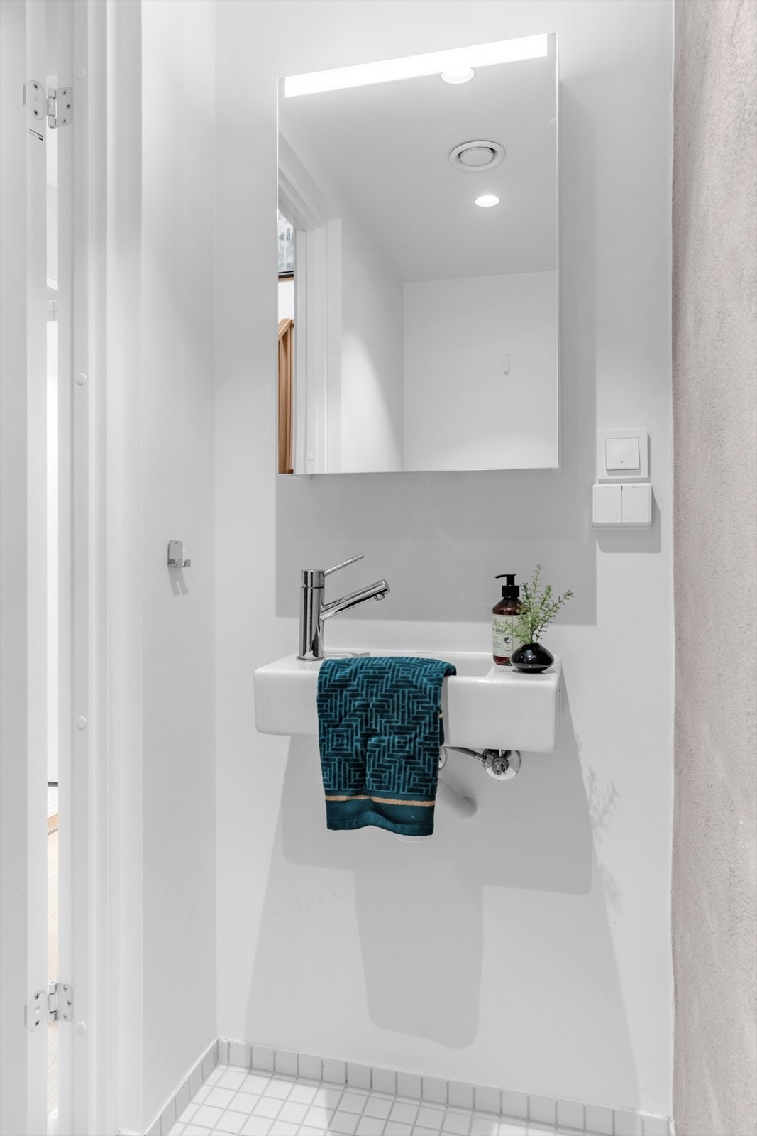 Rommet er utstyrt med veggmontert klosett, en funksjonell servant og et stilrent speilskap for god oppbevaring. Galleribilde