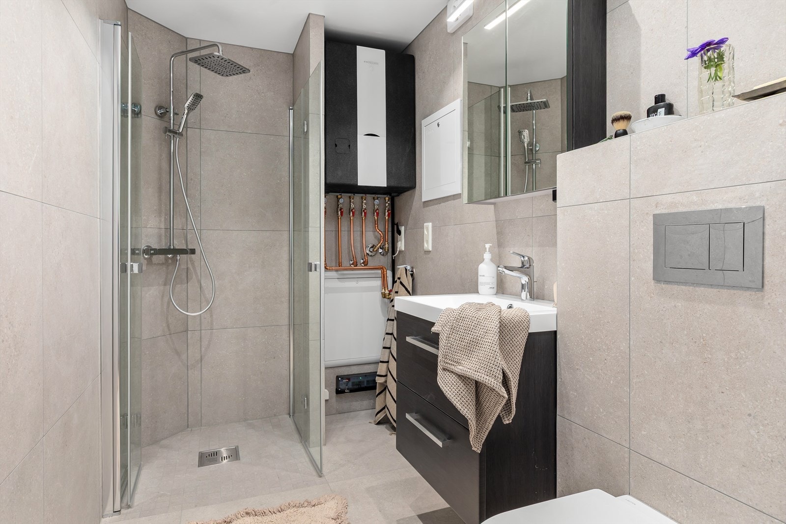 Badet ble renovert i 2025 og er utstyrt med en dusj på gulv med stilige dører i herdet glass, og et veggfestet klosett med innebygget sisterne. Galleribilde