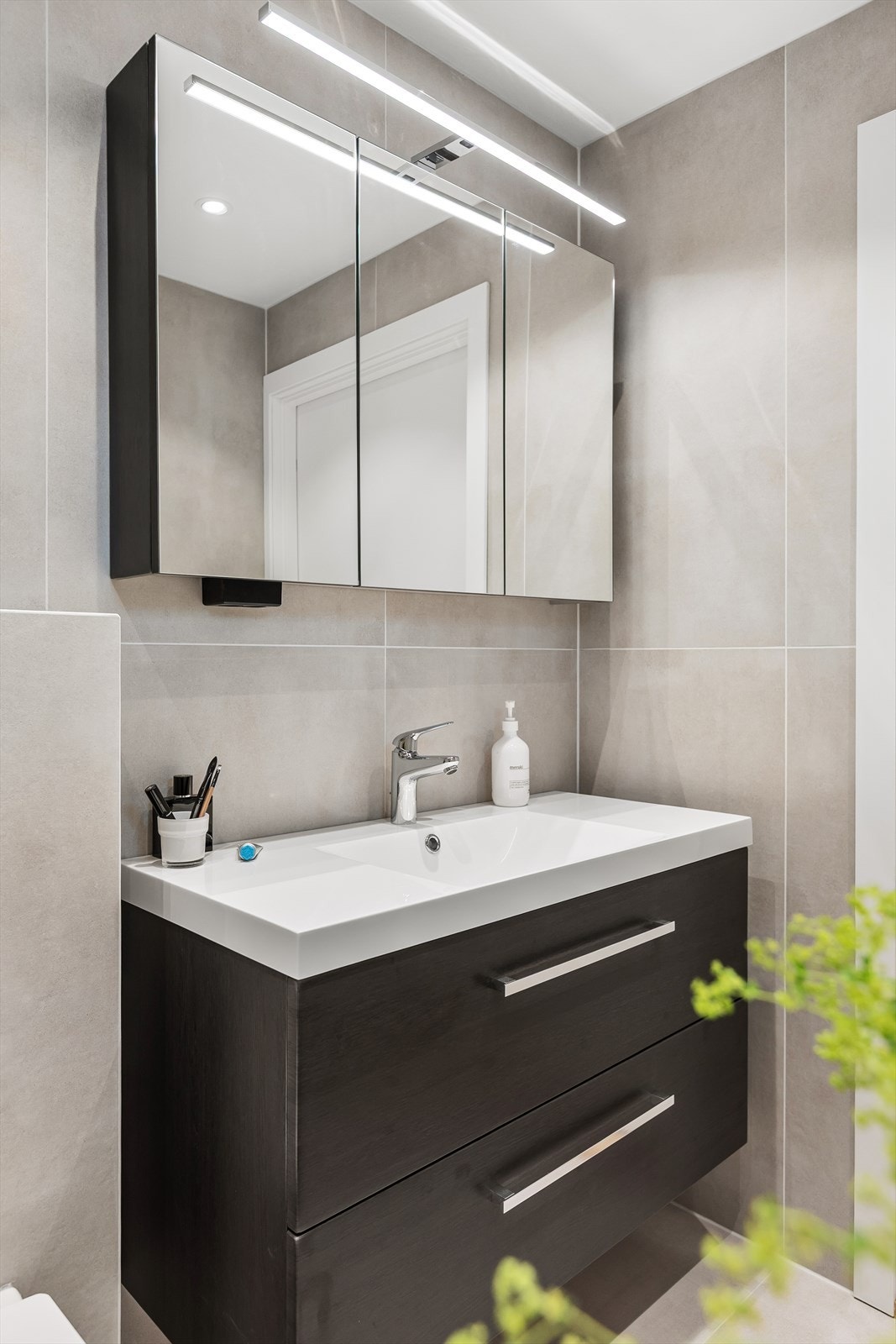 Benkeskap med glatte fronter og overskap med speilfronter for et moderne og funksjonelt uttrykk. Galleribilde