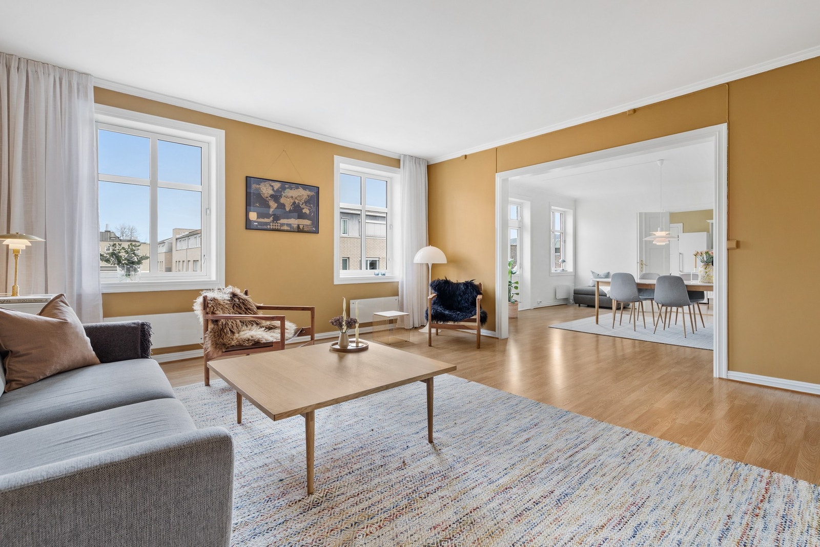 Stuen har en elegant kombinasjon av varme okergule vegger og hvite detaljer som gir rommet en lun atmosfære Galleribilde