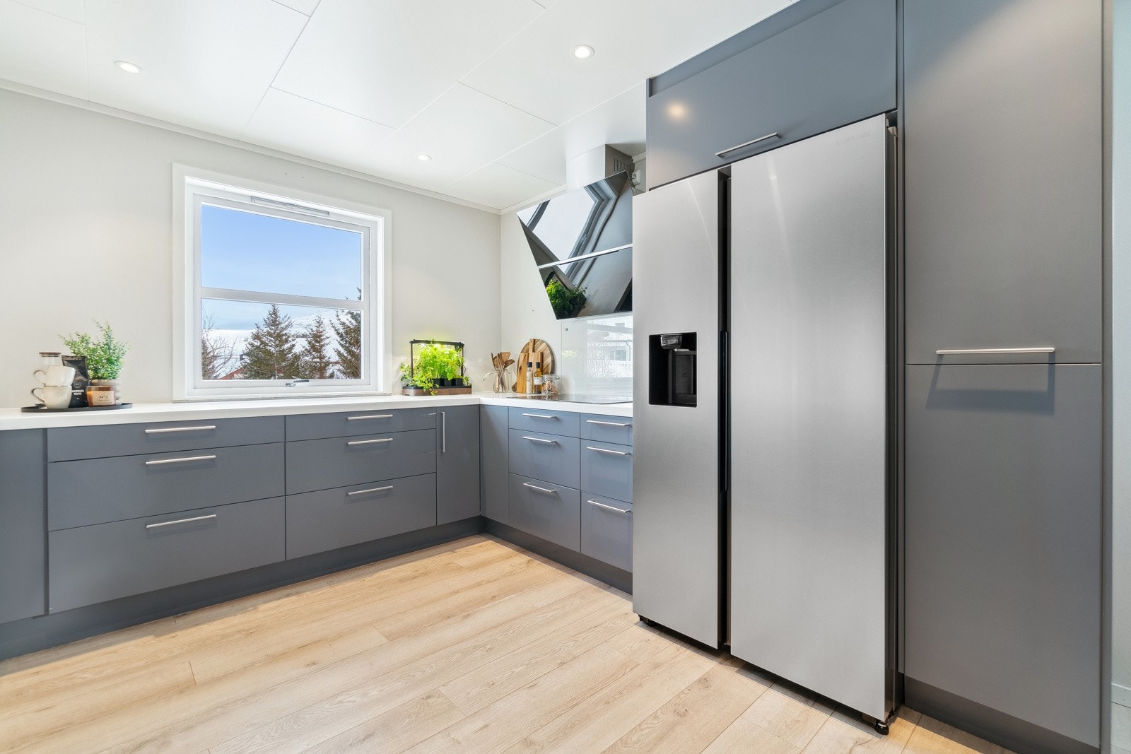 Kjøkkenet er utstyrt med moderne hvitevarer som oppvaskmaskin, induksjonstopp, mikrobølgeovn og stekeovn, alle integrert for å gi et ryddig og enhetlig uttrykk. Galleribilde