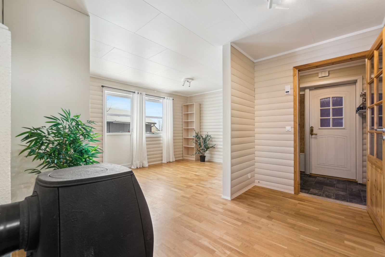 Entréen ønsker deg velkommen med sin praktiske utforming, hvor du har plass til en enkel garderobeinnredning for sko og jakker. Videre inn kommer du inn i en gang, med én av boligens stuer i en delvis åpen planløsning like til høyre. Galleribilde