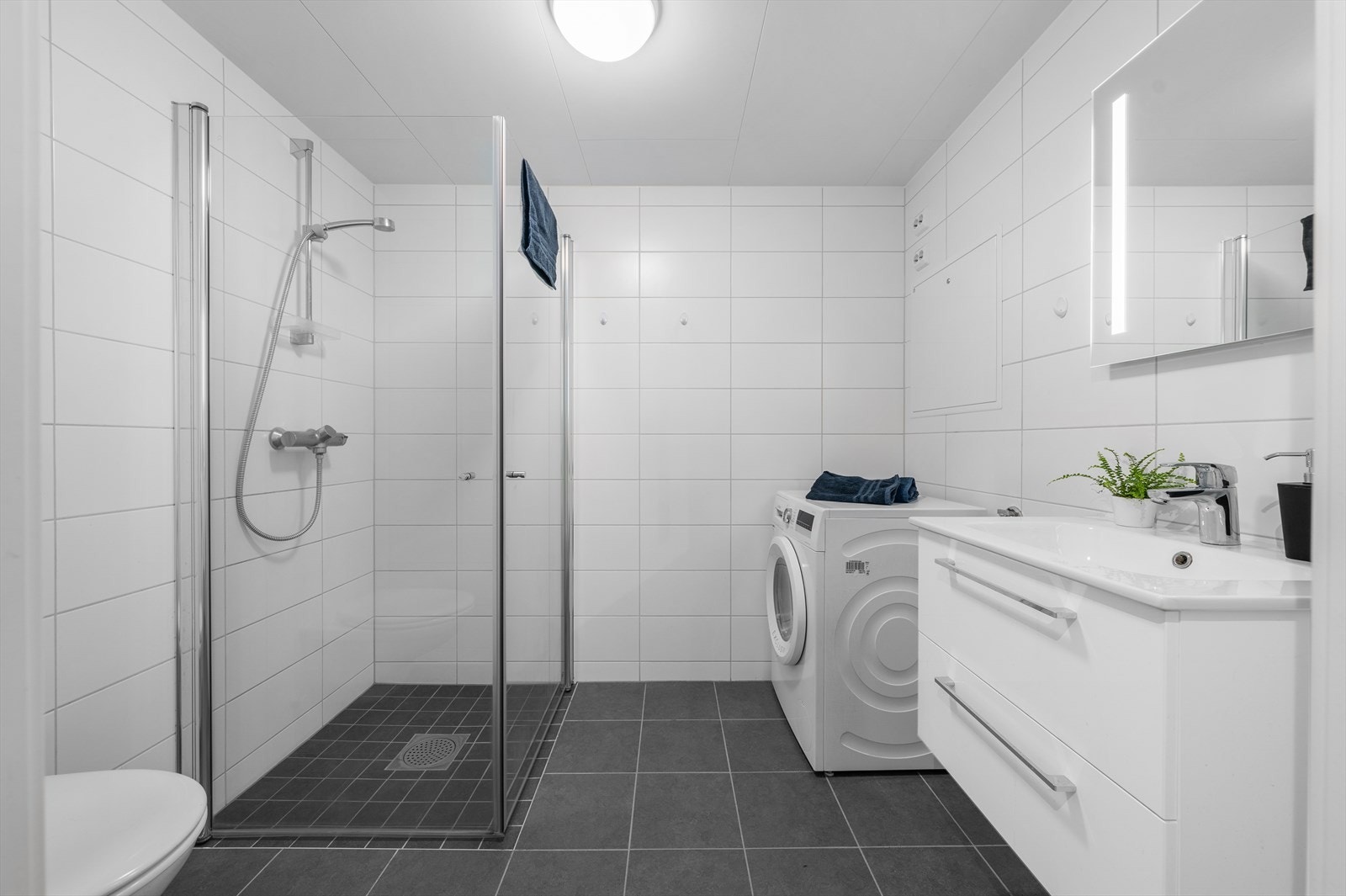 Flislagt bad i 2.etasje med wc, dusjhjørne, servantskap med speil og belysning, samt opplegg for vaskemaskin Galleribilde