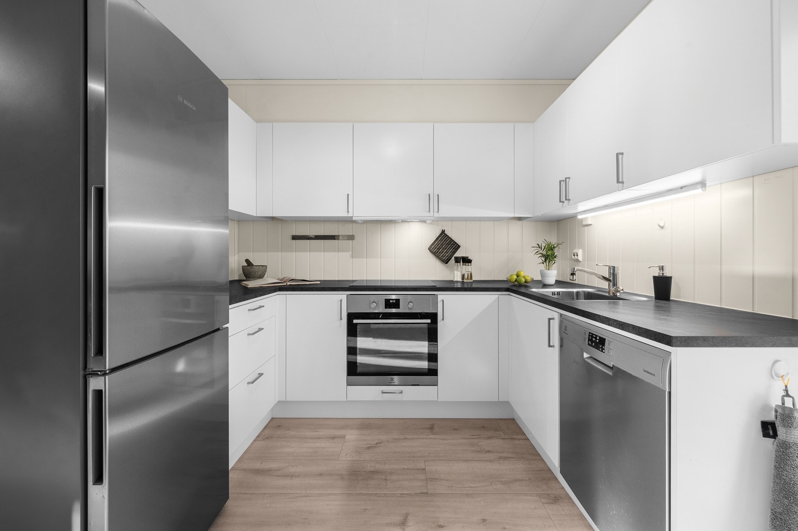 Laminat benkeplate med nedfelt stål oppvaskum og belysning under overskap. Galleribilde