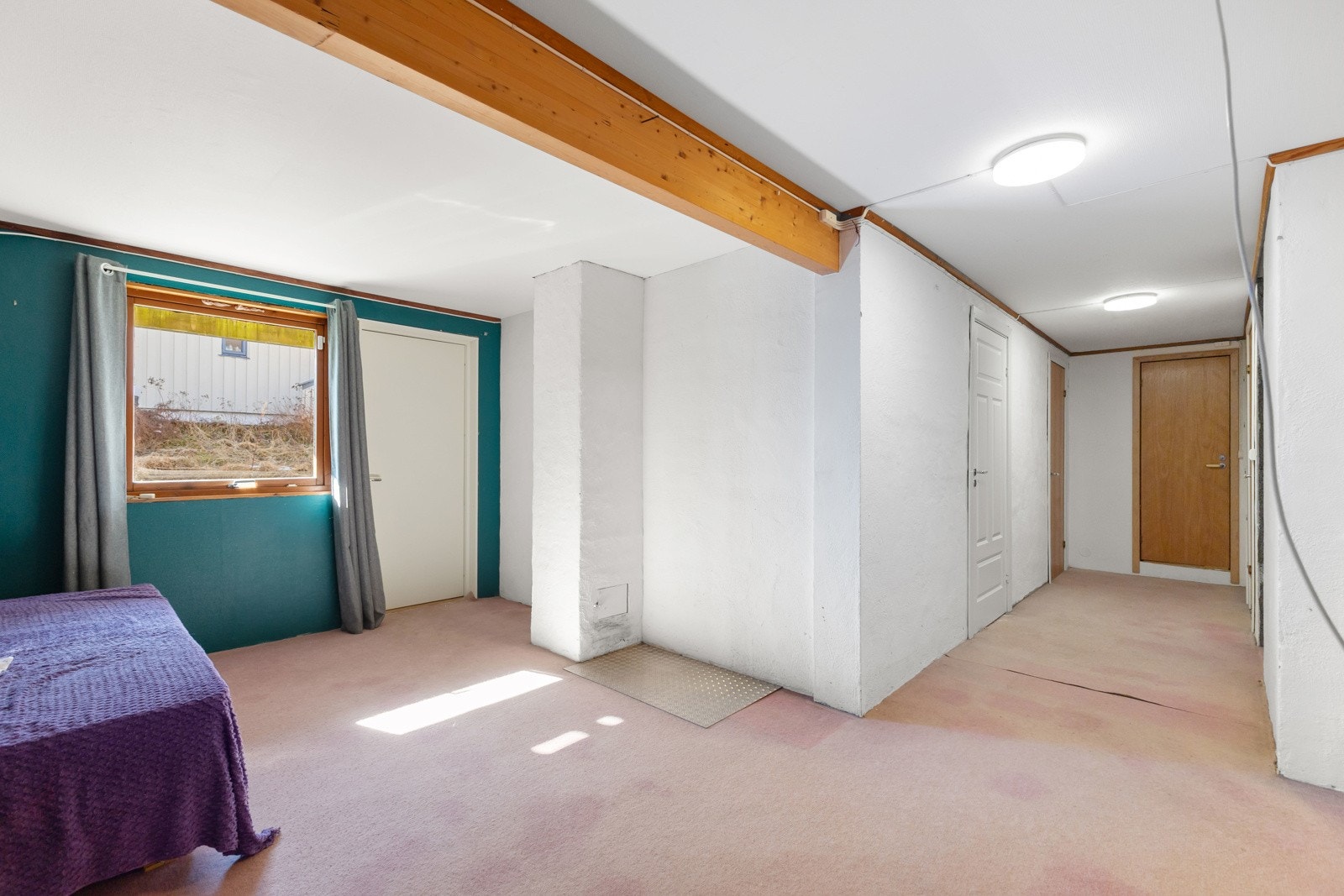 Lyst rom med teppebelagt gulv, hvite vegger og en grønn vegg med vindu. Galleribilde