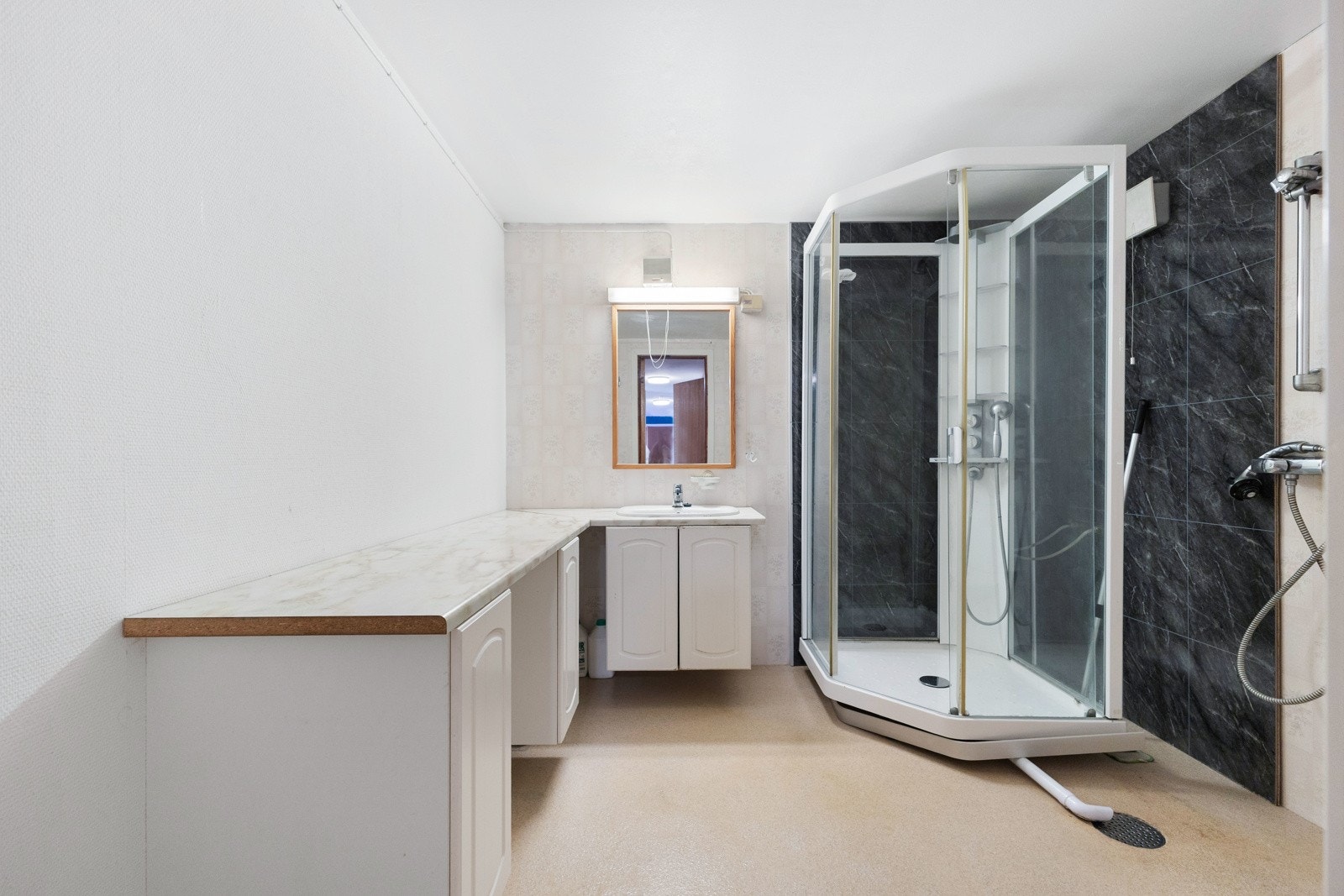 Bad med dusjkabinett, servant med underskap, speil med belysning og toalett. Galleribilde