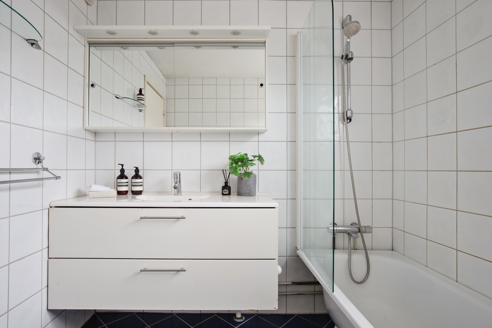 Badet er innredet med servantinnredning, speilskap og badekar med dusj Galleribilde