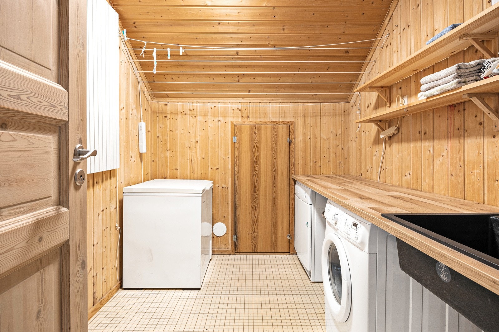 Oppvarmet og isolert vaskerom med store lagringsrom i bakkant via liten dør i bakgrunn integrert i huset. Galleribilde