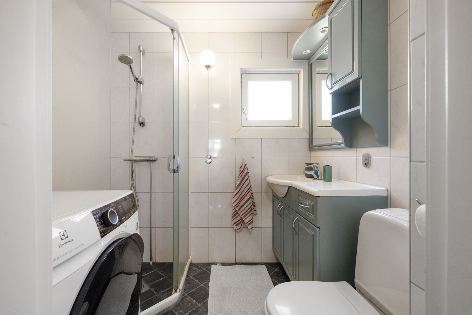 Lyst baderom med vindu, opplegg for vaskemaskin, og flott innredning. Galleribilde
