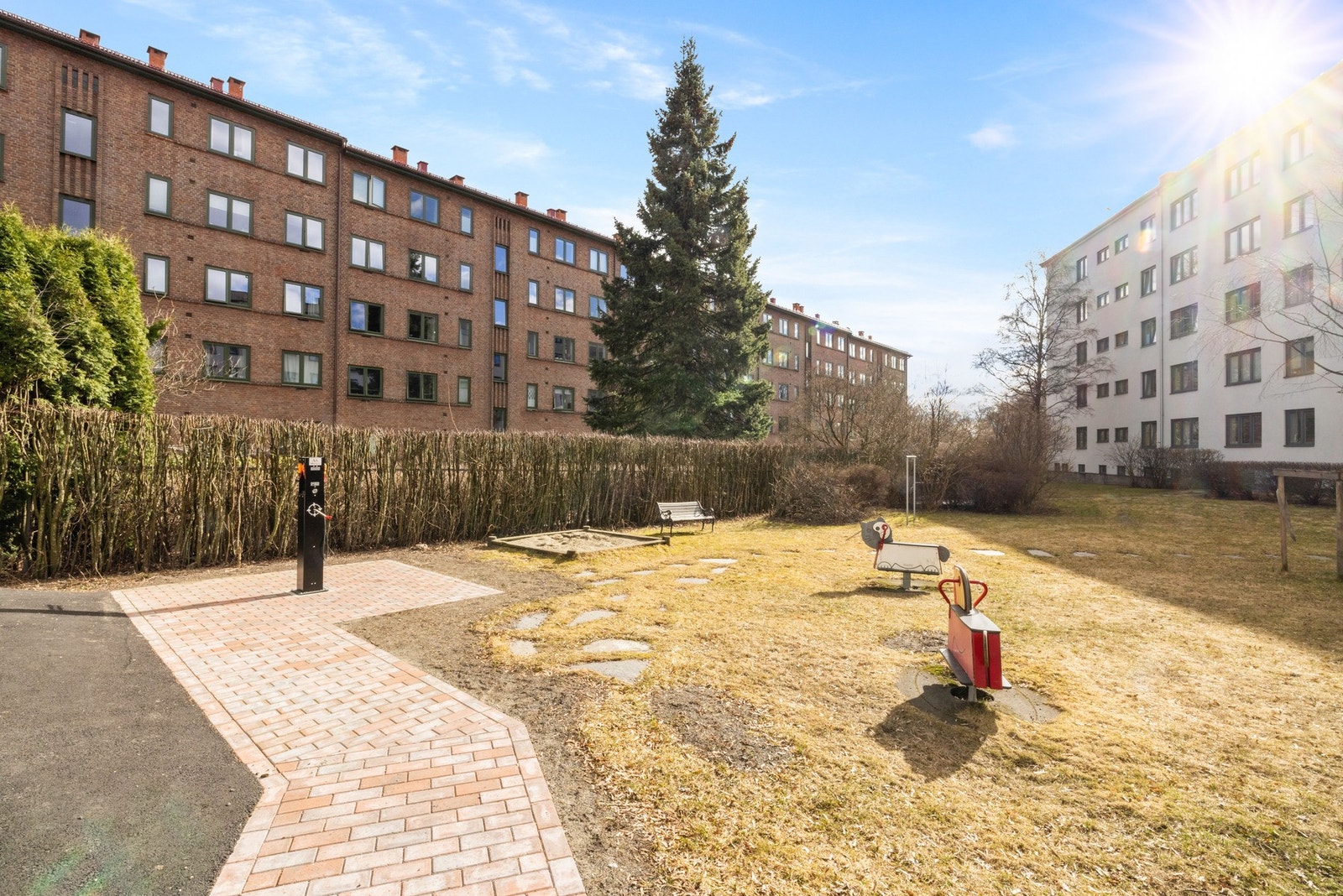 Pent opparbeidede fellesarealer med stasjon for sykkelservice, lekeapparater, sittegrupper, asfalterte veier og gressplen. Galleribilde