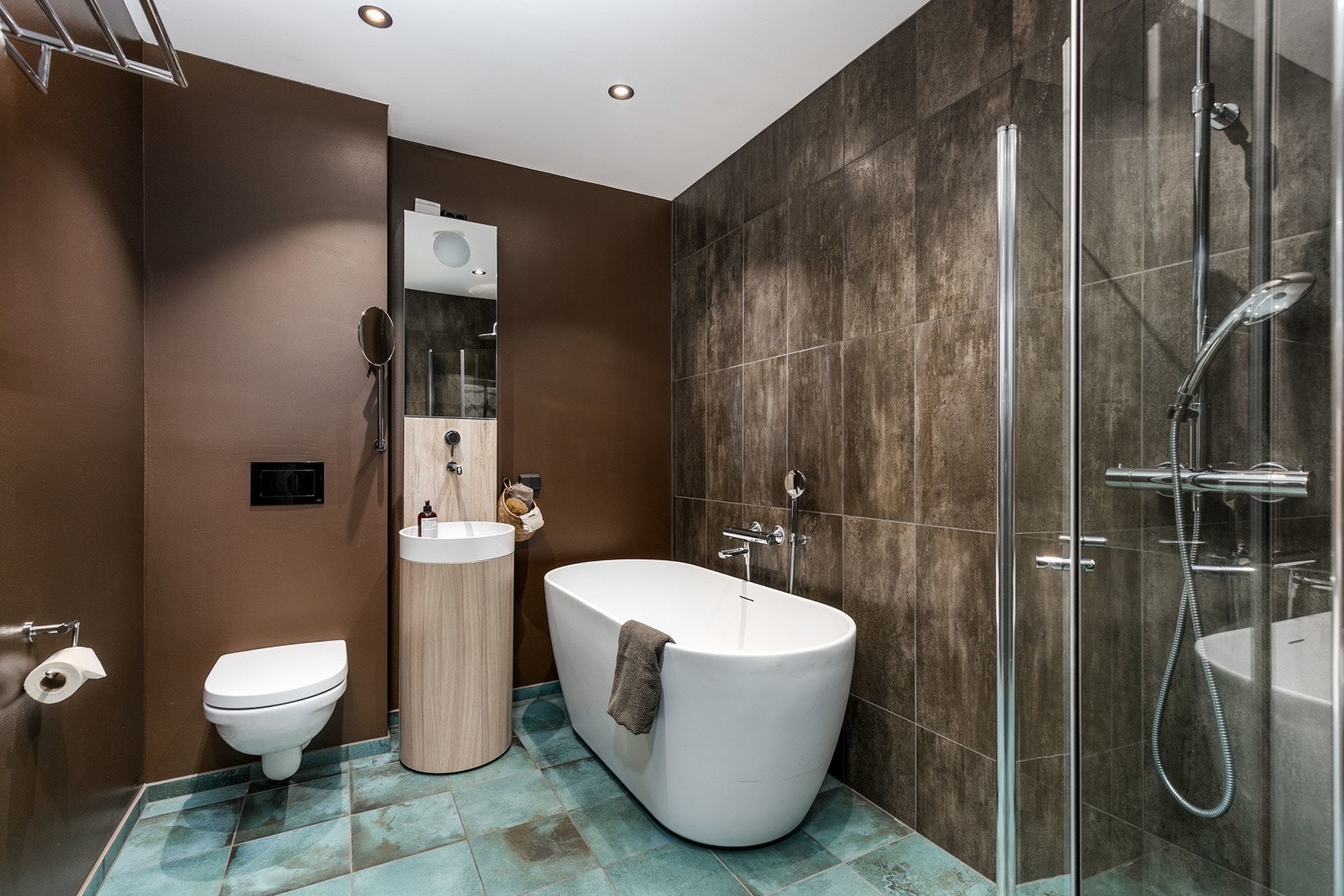 Innredningen består av gulvstående servantinnredning, speilskap med overlys, dusjhjørne, badekar og vegghengt toalett. Galleribilde