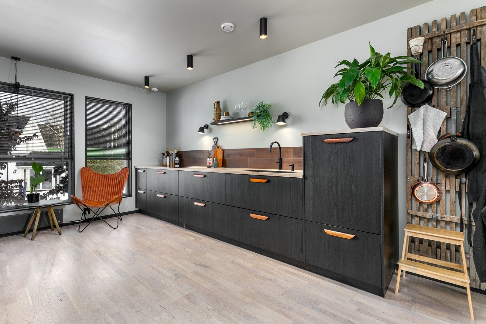 Innredning med mørke, glatte fronter og laminat heltre benkeplate med nedfelt oppvaskkum med ett-greps kjøkkenarmatur (Quooker). Galleribilde