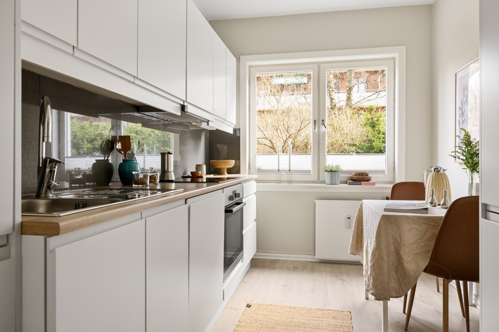 Moderne kjøkken fra 2017 med hvite, slette fronter uten grep, overskap med benkebelysning og fliser på vegg som gir et stilrent uttrykk. Galleribilde