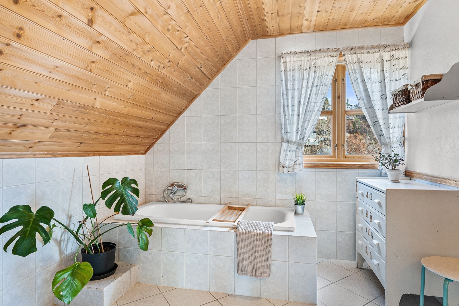 Badet på loftet har gulvfliser med varmekabler, veggfliser og panel i taket. Galleribilde