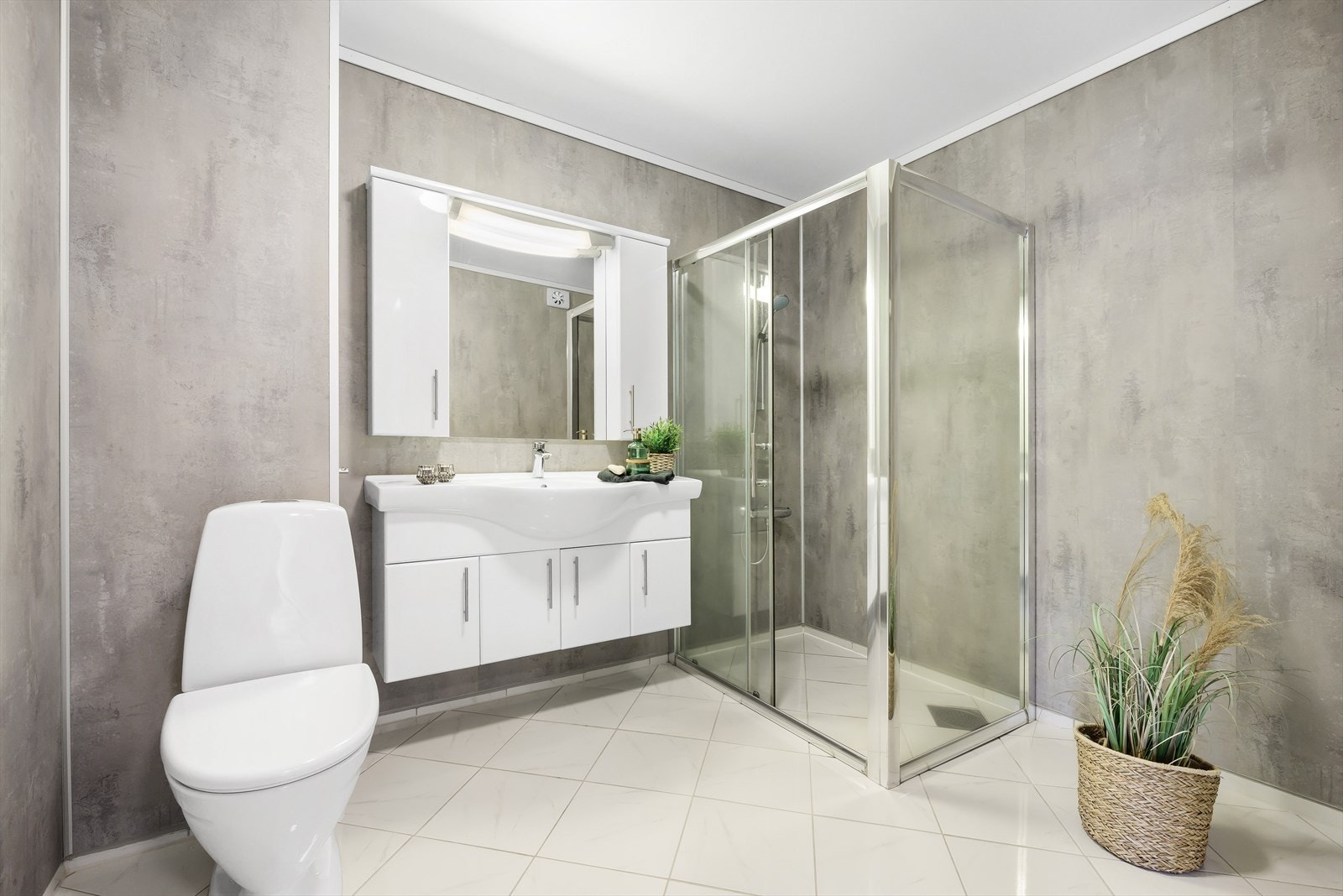 Badet er utstyrt med toalett, servant med overskap/speil og dushjørne. Galleribilde