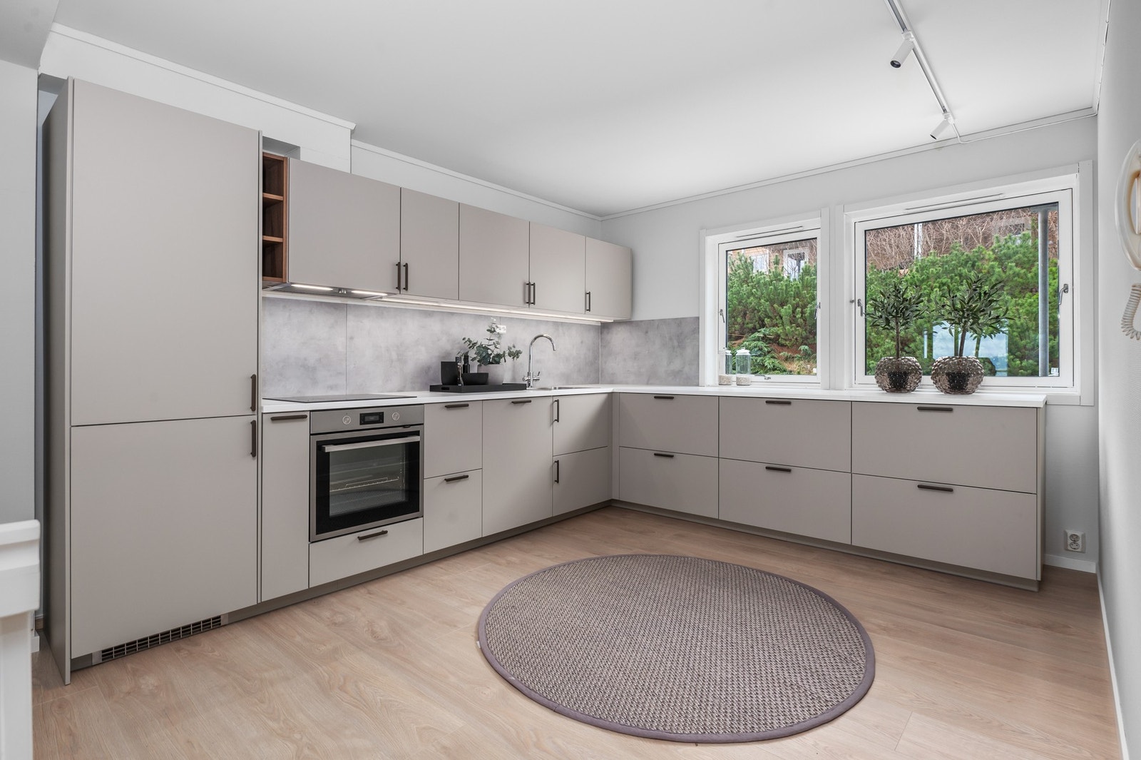 Kjøkkeninnredningen er utført i moderne fargevalg med glatte fronter og benkeplate av laminat. Galleribilde