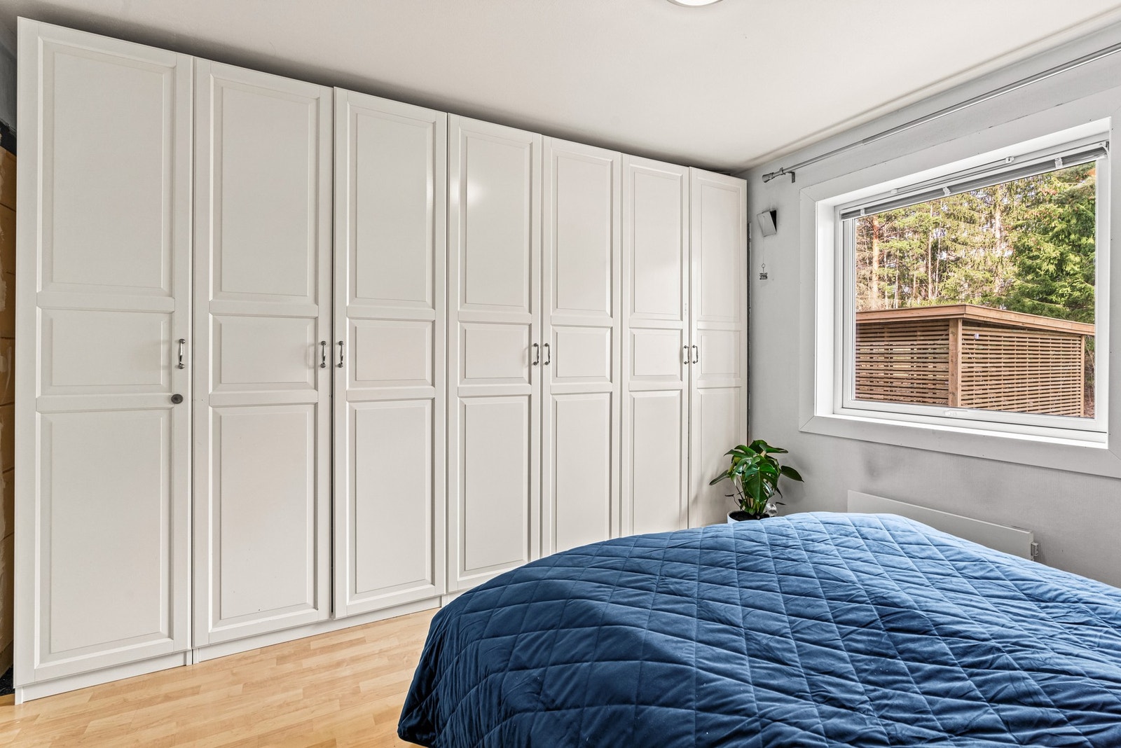 Hovedsoverommet har en bredrekke med hvite garderobeskap Galleribilde