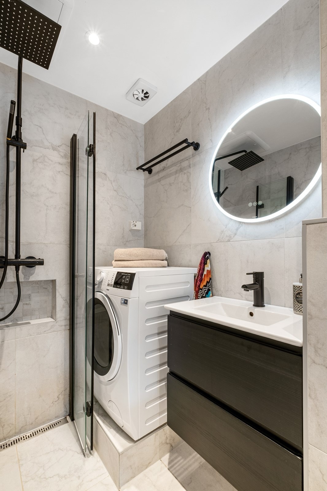 Baderommet er innredet med vegghengt klosett, servant med innredning, speil m/ lys og dusjhjørne med svingbare glassdører. Opplegg for vaskemaskin. Elektrisk styrt vifte. Galleribilde