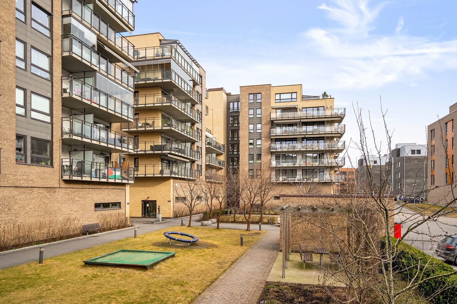 Pent opparbeidet bakgård med plen og beplantning, lekeapparater og sittegrupper Galleribilde