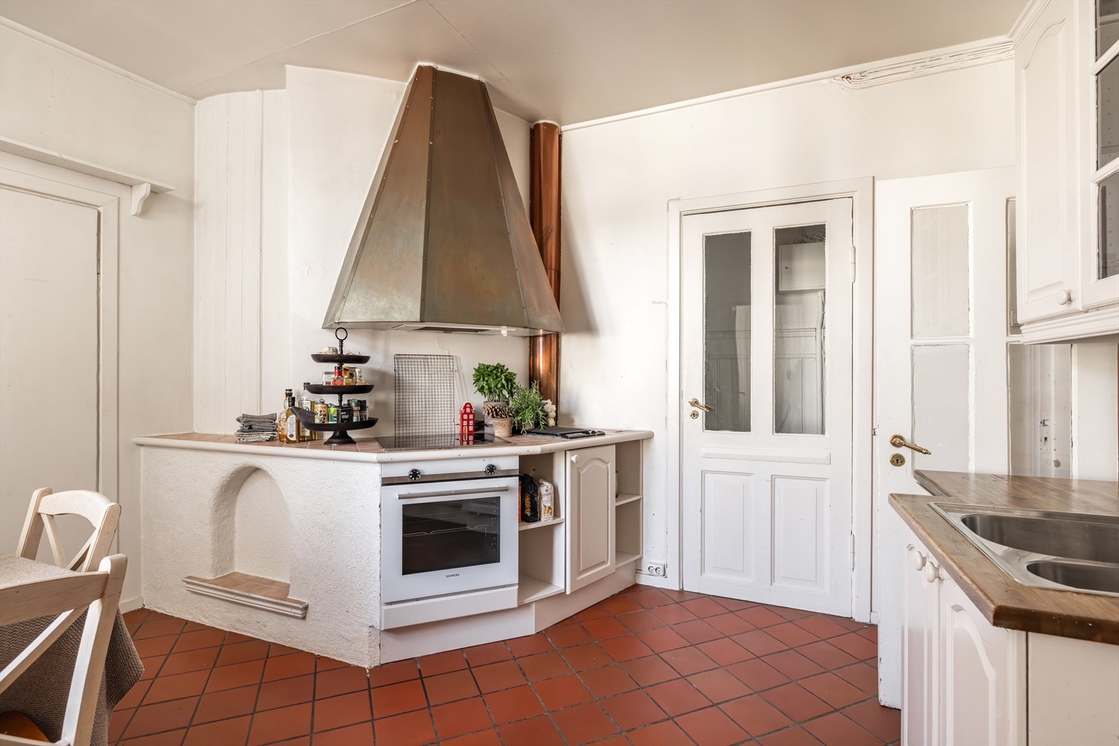 Kjøkkeninnredningen har eldre, profilerte fronter og en solid trebenkeplate med nedfelt oppvaskkum. Fra kjøkkenet er det adkomst til gang som leder mot baktrapp. Galleribilde