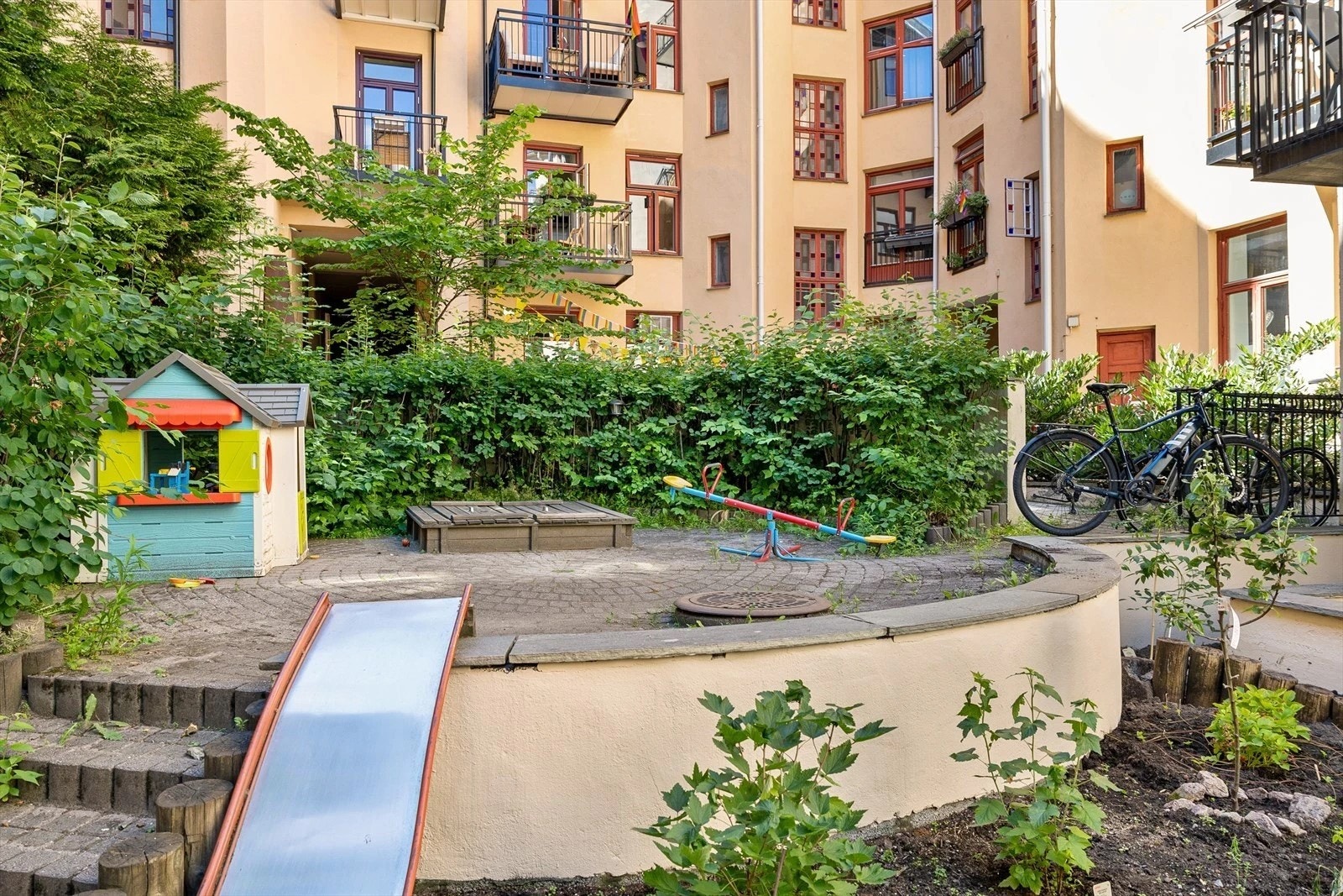 Opparbeidet tomt med med brosteinsbelagt adkomst og bakgård med sittegrupper samt diverse busker og beplantninger. Galleribilde