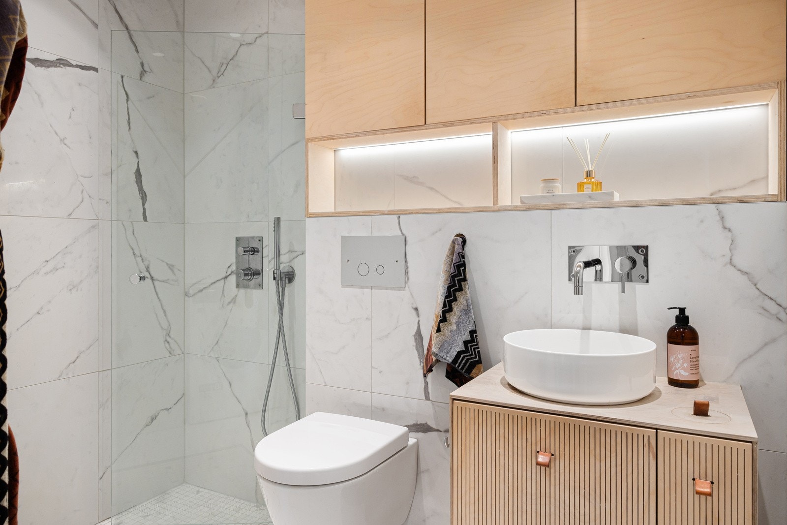 Attraktivt bad innredet med vegghengt servantskap i bjørkefinér med utenpåliggende vask og integrert ett-greps armatur. Innebygget sisterne med vegghengt toalett. Opplegg for vaskemaskin. Galleribilde