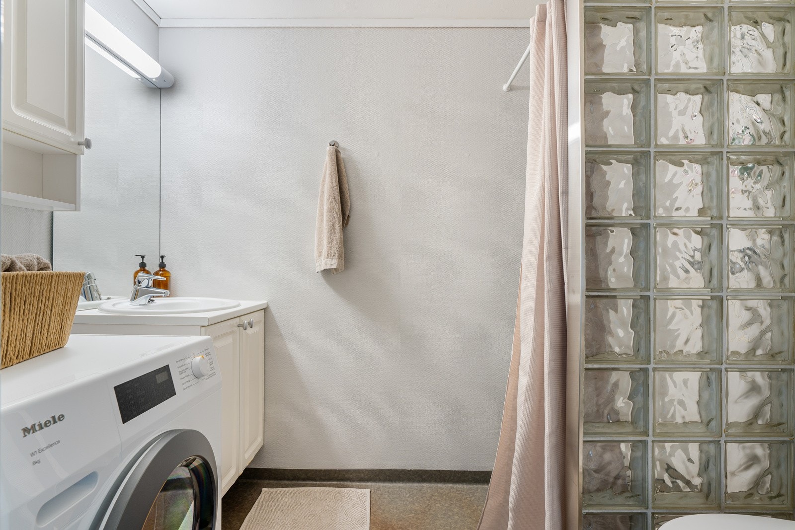 Baderommet ligger med adkomst fra gangen, og er innredet med dusjhjørne, opplegg for vaskemaskin, toalett og en lys baderomsinnredning. Galleribilde