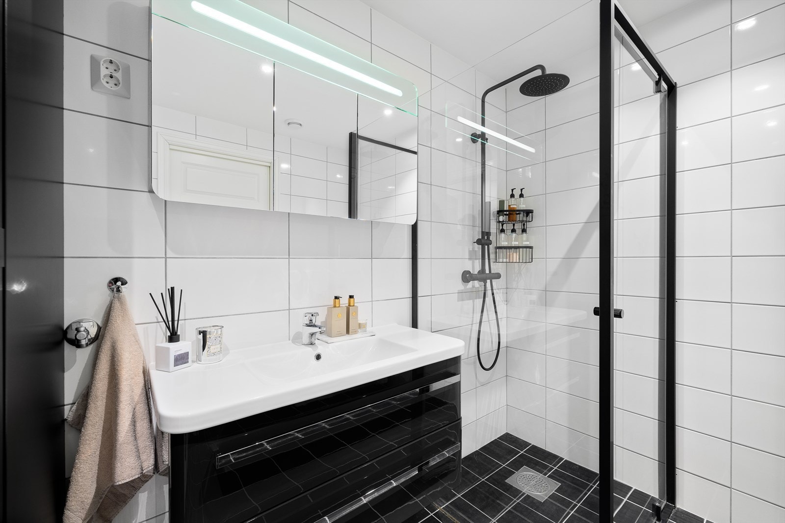 Badet inneholder vegghengt servantinnredning med skuffer, vegghengt baderomsmøbel, dusjhjørne med vegghengt dusjarmatur og vegghengt toalett. Galleribilde