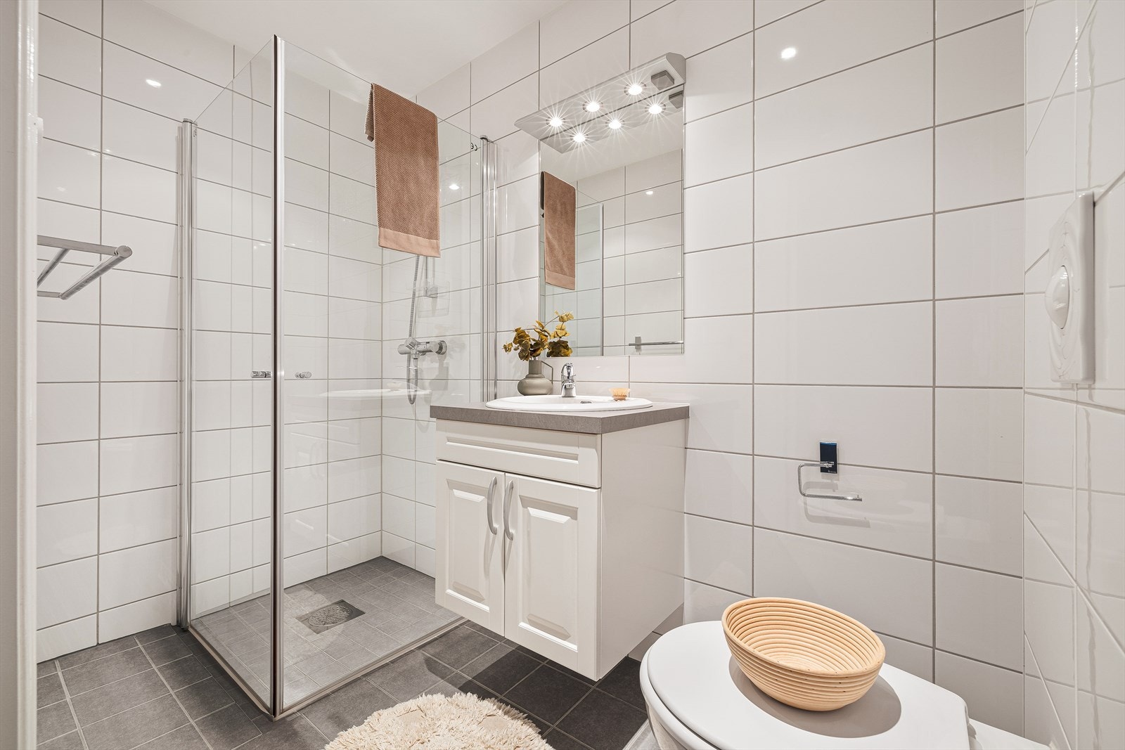 Delikat, helfliset bad med varme i gulv, spotter i himling, vegghengt toalett og servant, samt dusjnisje med foldedører i glass. Galleribilde