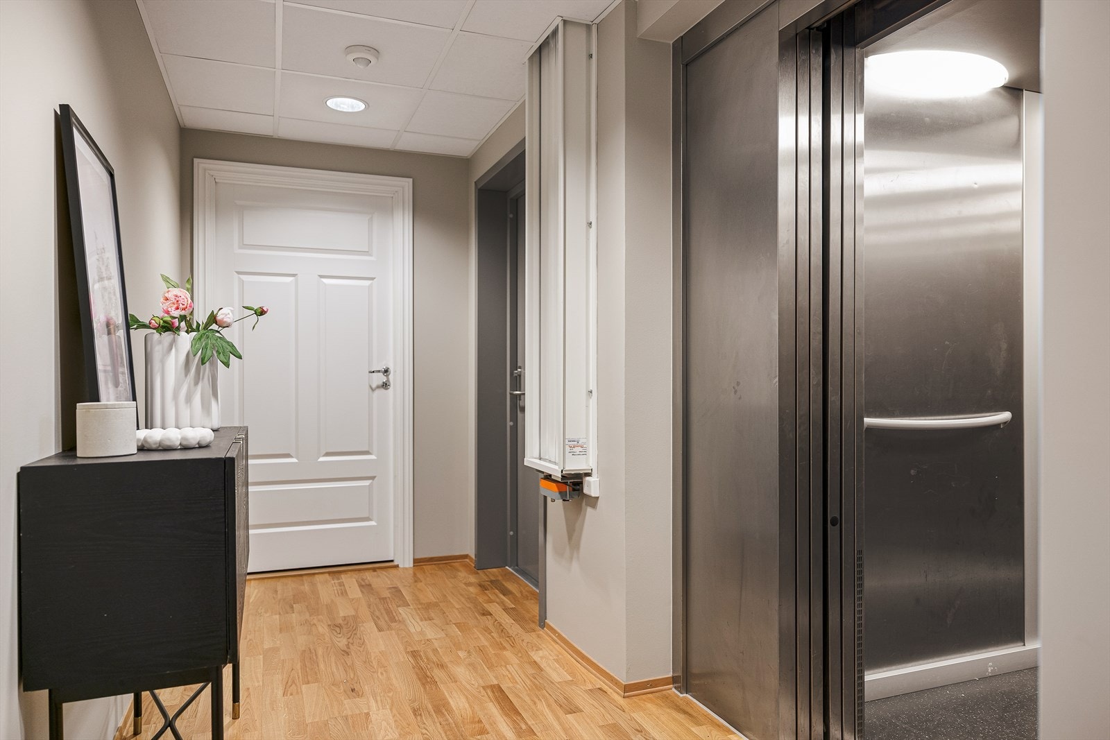 Privat entré like ut av heisen. Det er kun aktuell leilighet som kan ta heis til 7.etg, da med egen kode. Heisen tar deg direkte fra garasjen, fellesarealene eller Kiwi, til entréen. Hvit, profilert dør inn til privat bod. Galleribilde