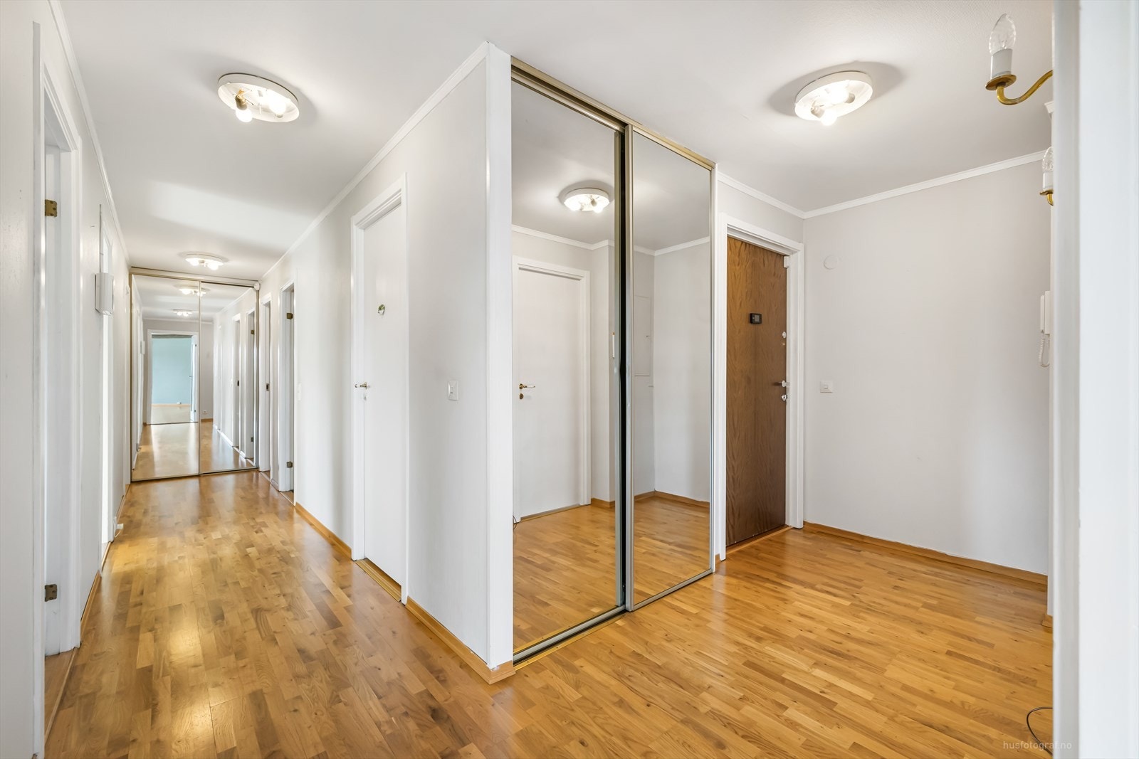 Romslig entre og gang med enkle garderobeløsninger med skyvedører. Galleribilde