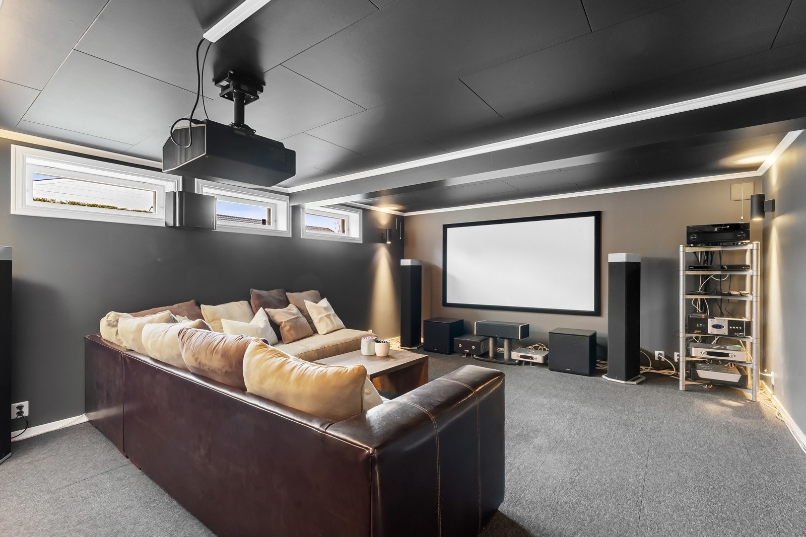 Kjellerstuen er idag innredet som en hjemmekino med lerret, lydanlegg og en romslig sofagruppe Galleribilde