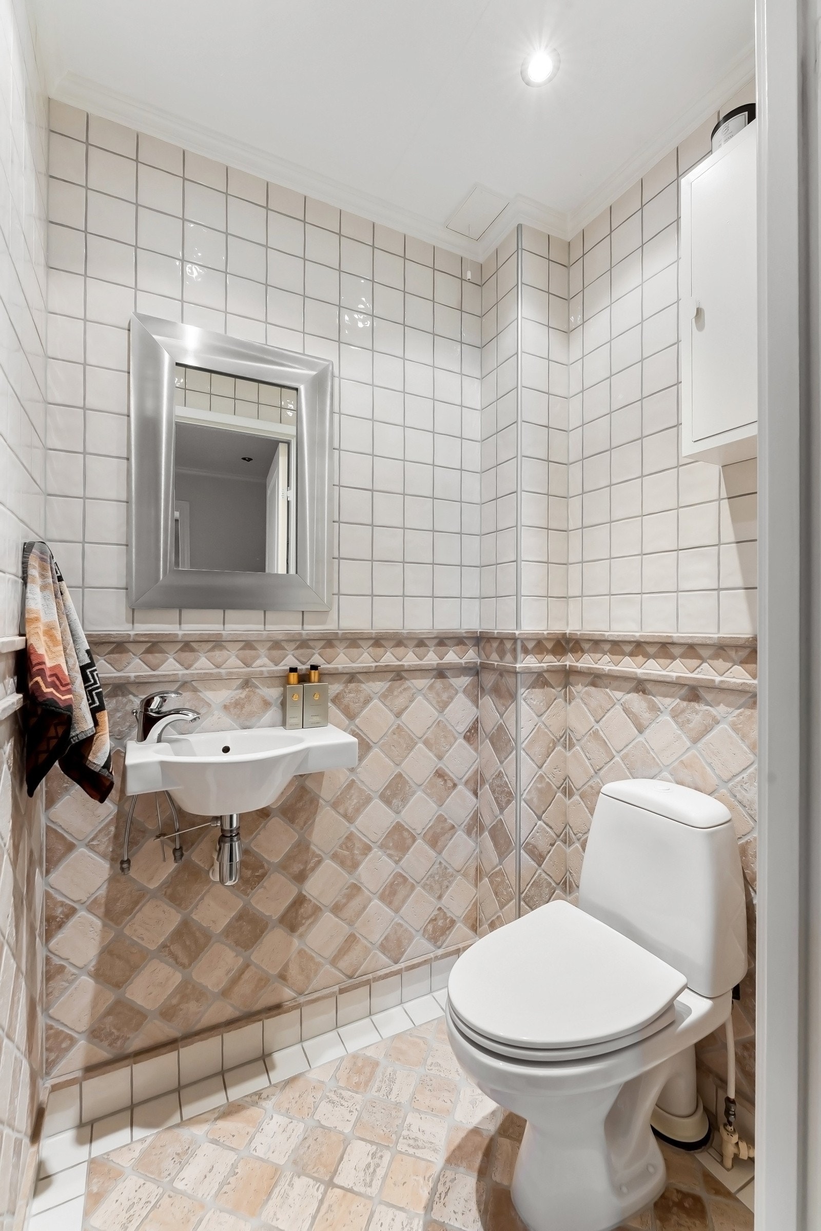 Toalettrommet med adkomst fra entréen har flislagte overflater, varmekabler i gulvet og er innredet med gulvmontert toalett, vegghengt servant og speil Galleribilde