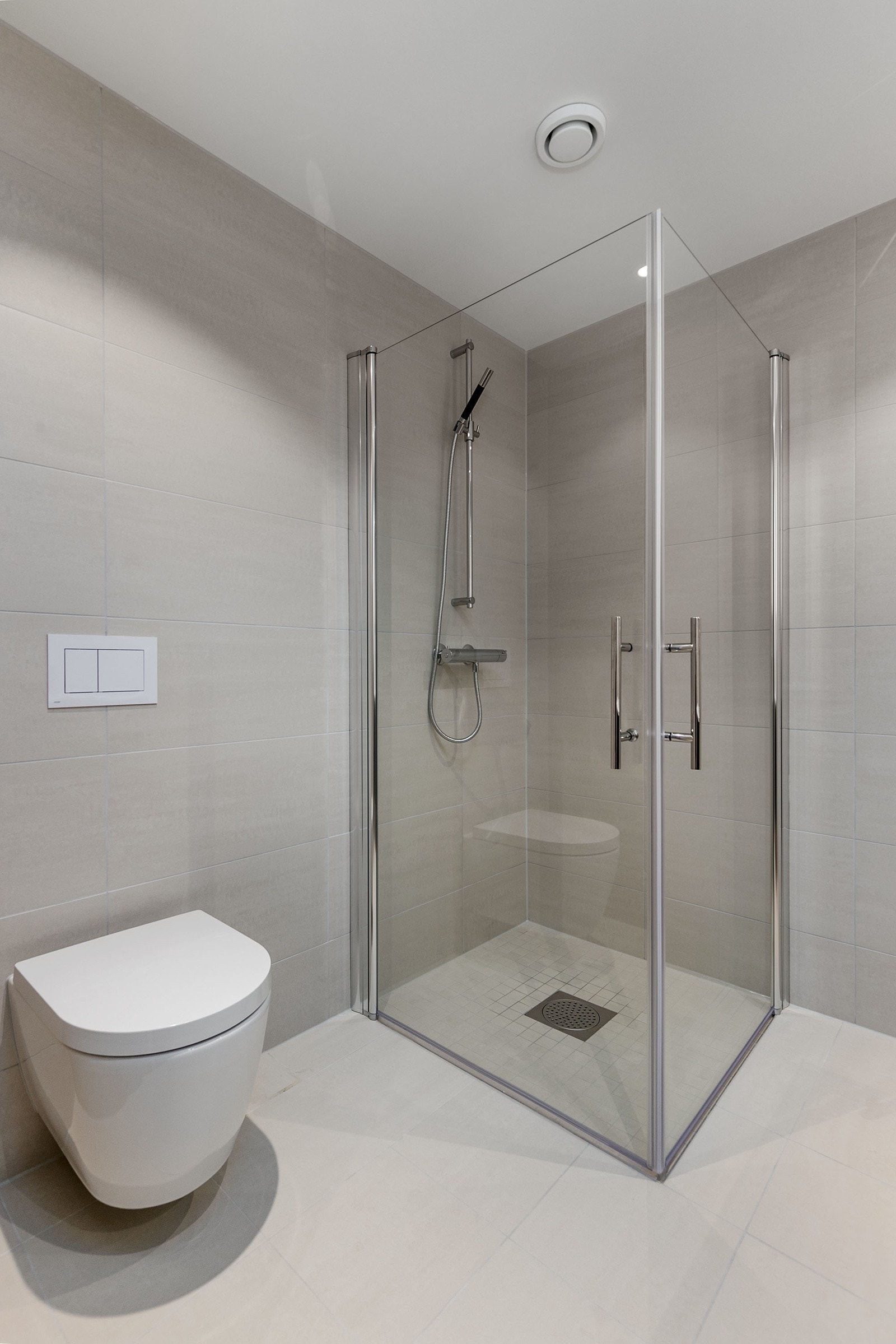Rette dusjvegger i herdet glass, som kan slås inn mot vegg og med profiler i krom. Vegghengt toalett. Bilde fra leilighet 303 Galleribilde