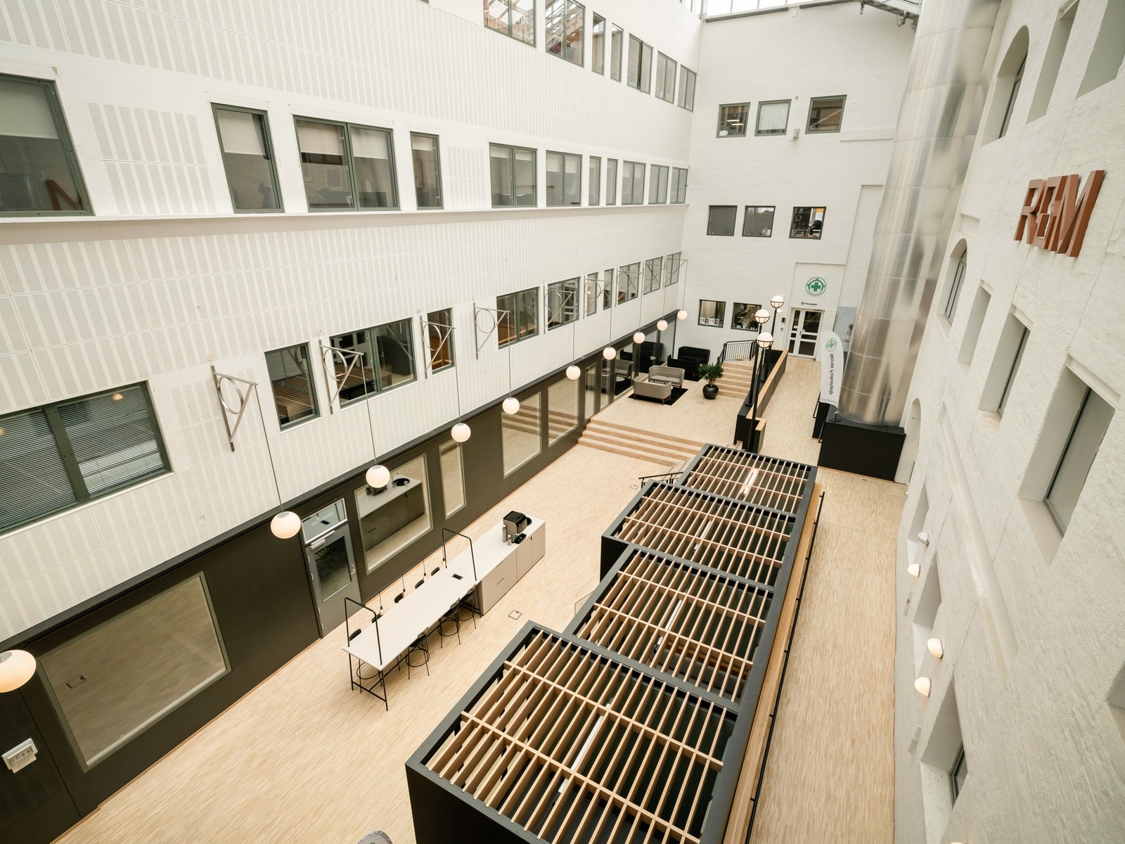 Felles sosial sone tilgjengelig for alle kontorbrukere i bygget, utstyrt med flere arbeidspoder for fleksibel bruk. Galleribilde