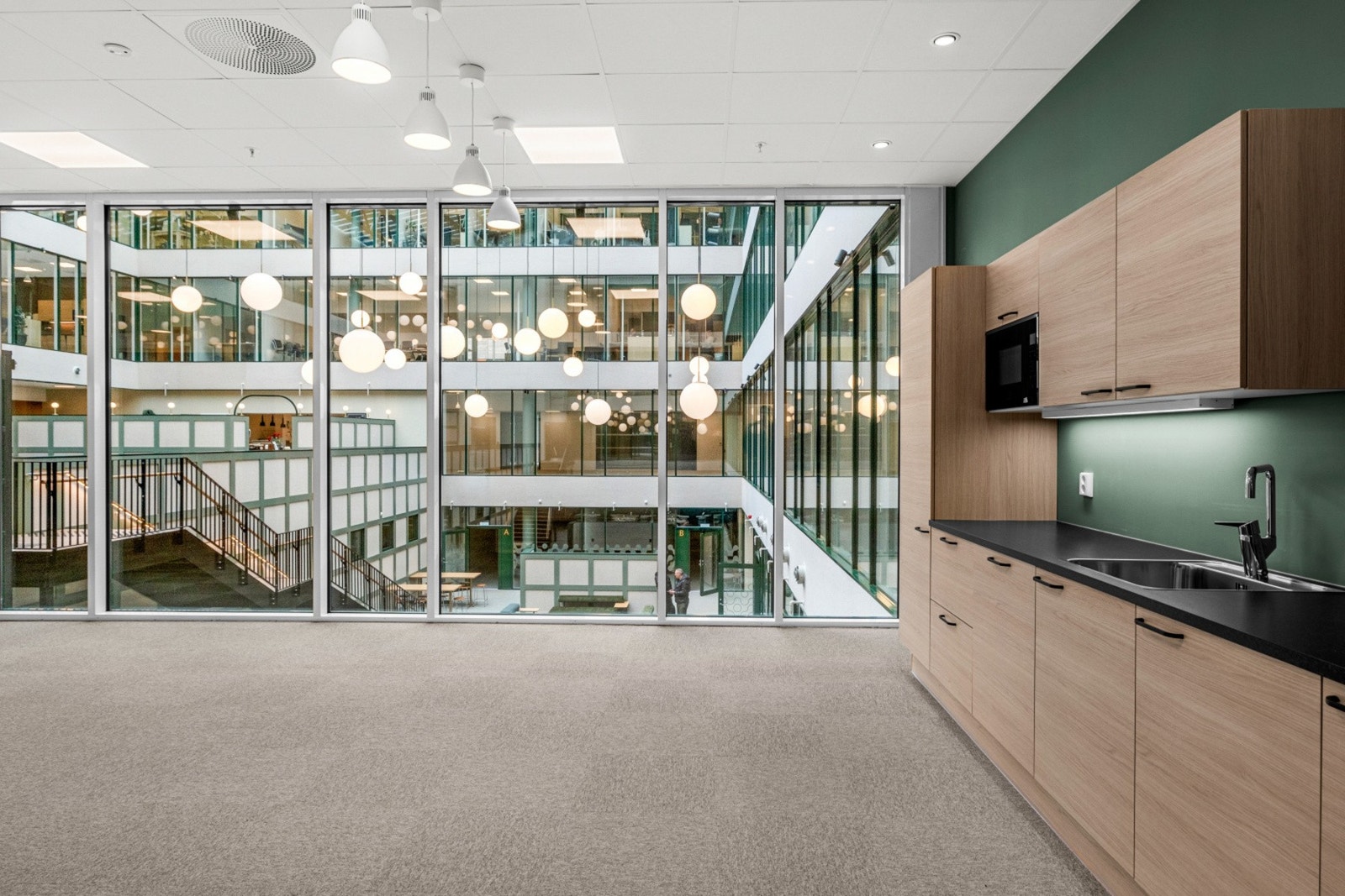 I etasjen er det etablert flotte og romslige kjøkken og tilhørende sosial sone, ett på hver side av atriet. Begge ligger skjermet slik at støy begrenses mellom kjøkken og arbeidsstasjoner. Galleribilde