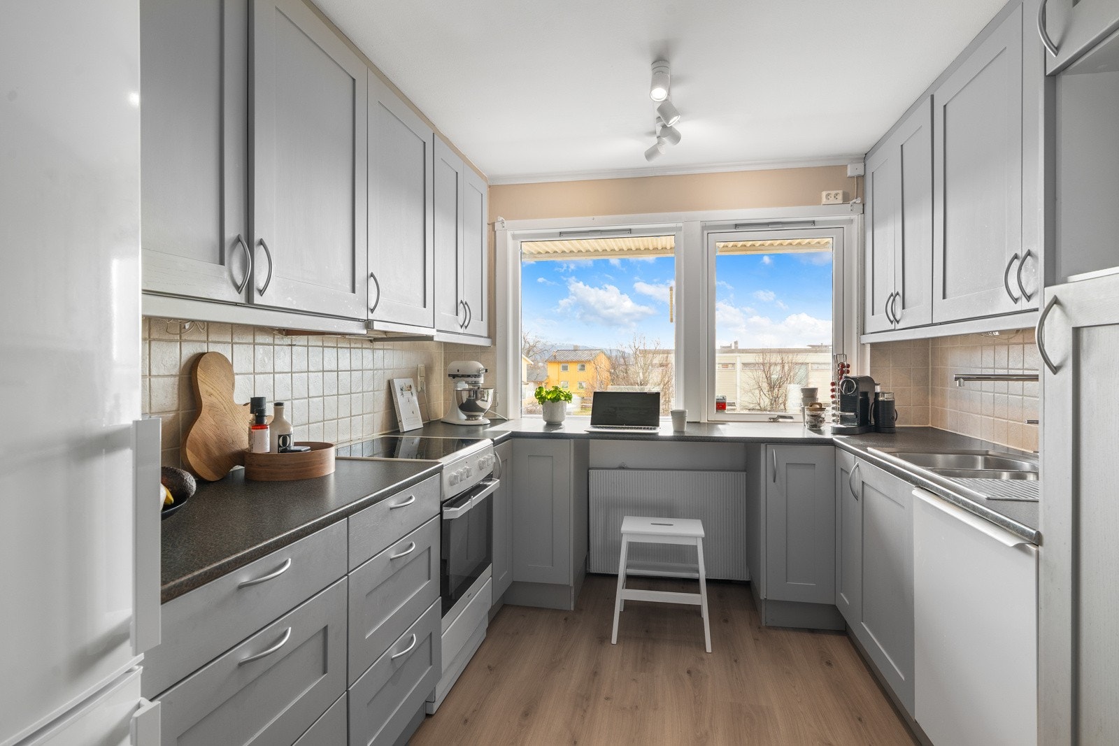 Kjøkkenet har en grå og tidløs innredning med profilerte fronter og medfølgende hvitevarer i form av stekeovn og kjøle- og fryseskap. Galleribilde