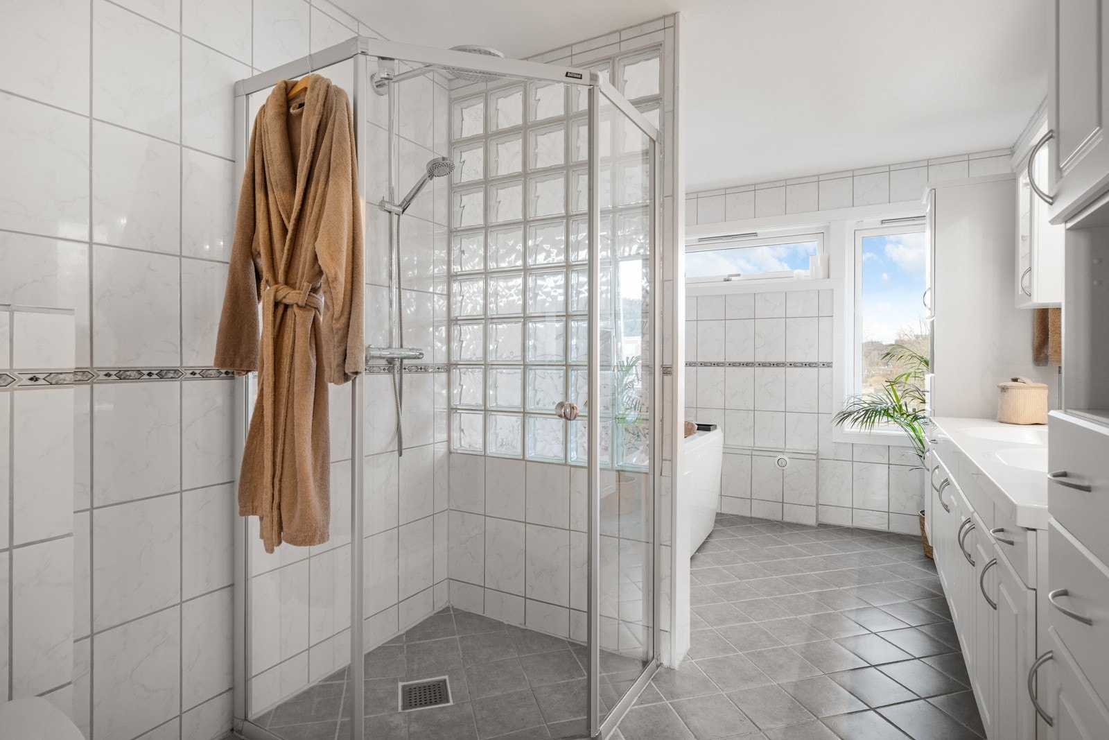 Badet er utstyrt med et romslig dusjhjørne, vegghengt toalett og en lys baderomsinnredning med 2 vasker samt godt med skapplass. Galleribilde