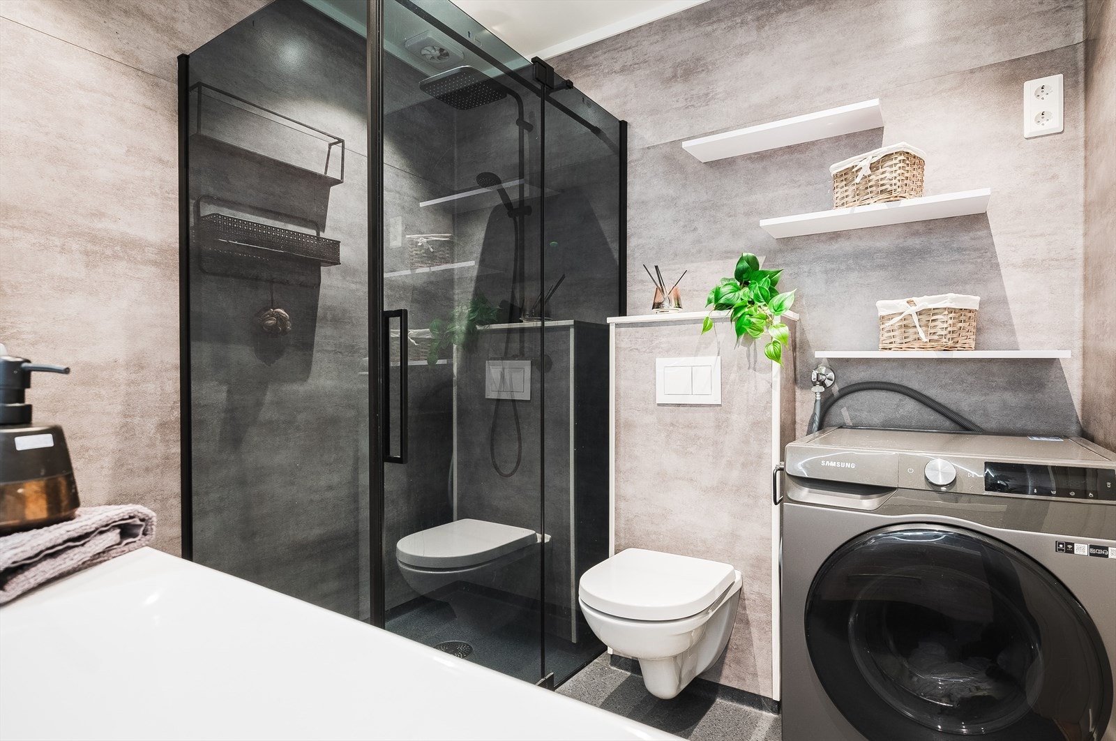 Badet har installasjoner med veggmontert toalett, dusjhjørne med fossefalldusj og glassdører, samt opplegg for vaskemaskin. Galleribilde